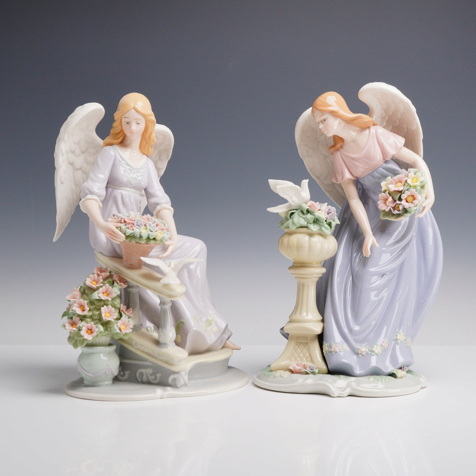 2pc Member's Mark Hand-Painted Porcelain Angel Figurines: A pair of hand-painted glazed porcelain angel figurines produced for Member's Mark and distributed by Sam's West, Inc. The first figurine depicts a celestial angel seated on a light gray architectural