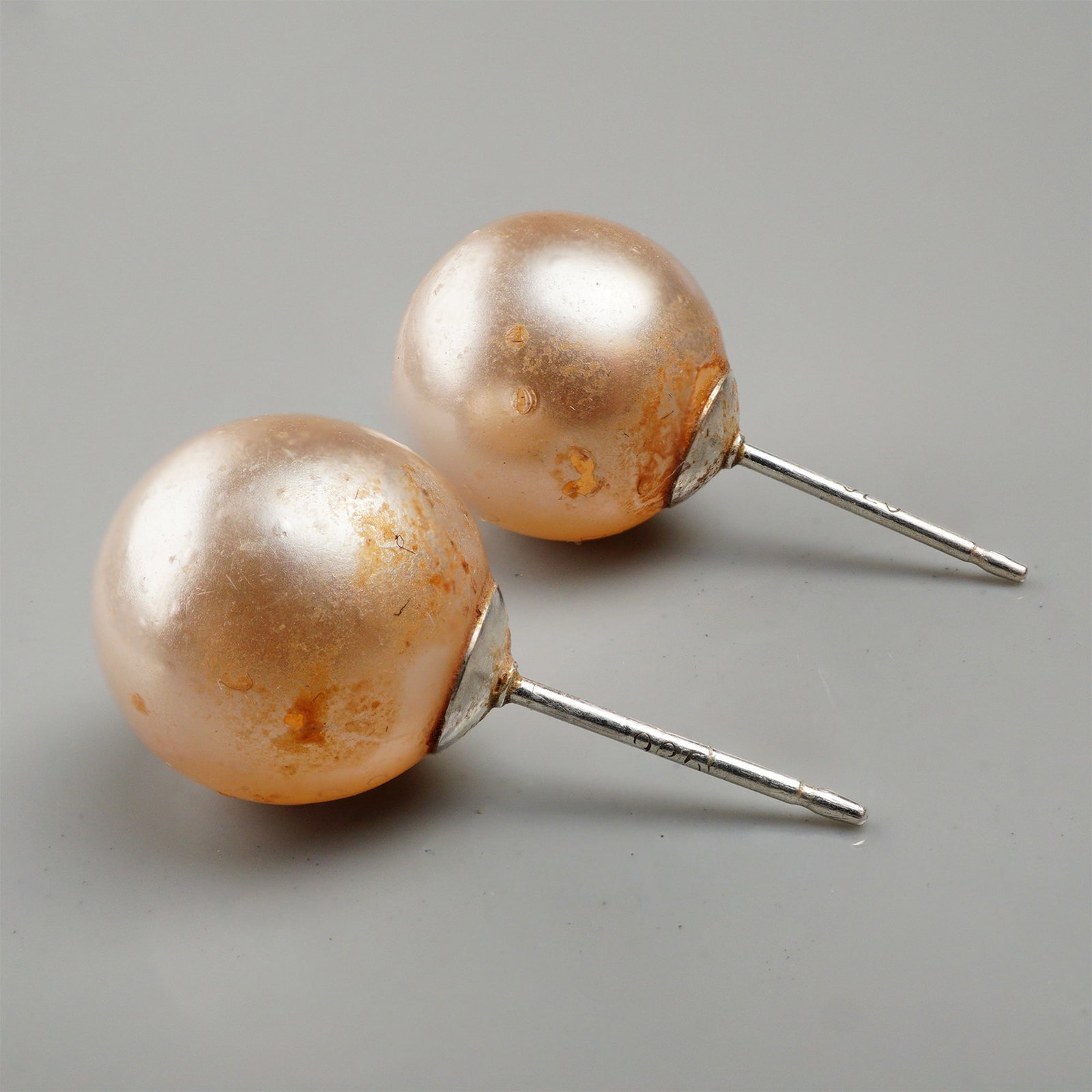 A Pair of Sterling Silver Pink Freshwater Cultured Pearl Stud Earrings: A pair of stud earrings featuring spherical pink freshwater cultured pearls set on sterling silver posts. The posts are clearly marked 925, confirming the sterling silver material. The style is contem