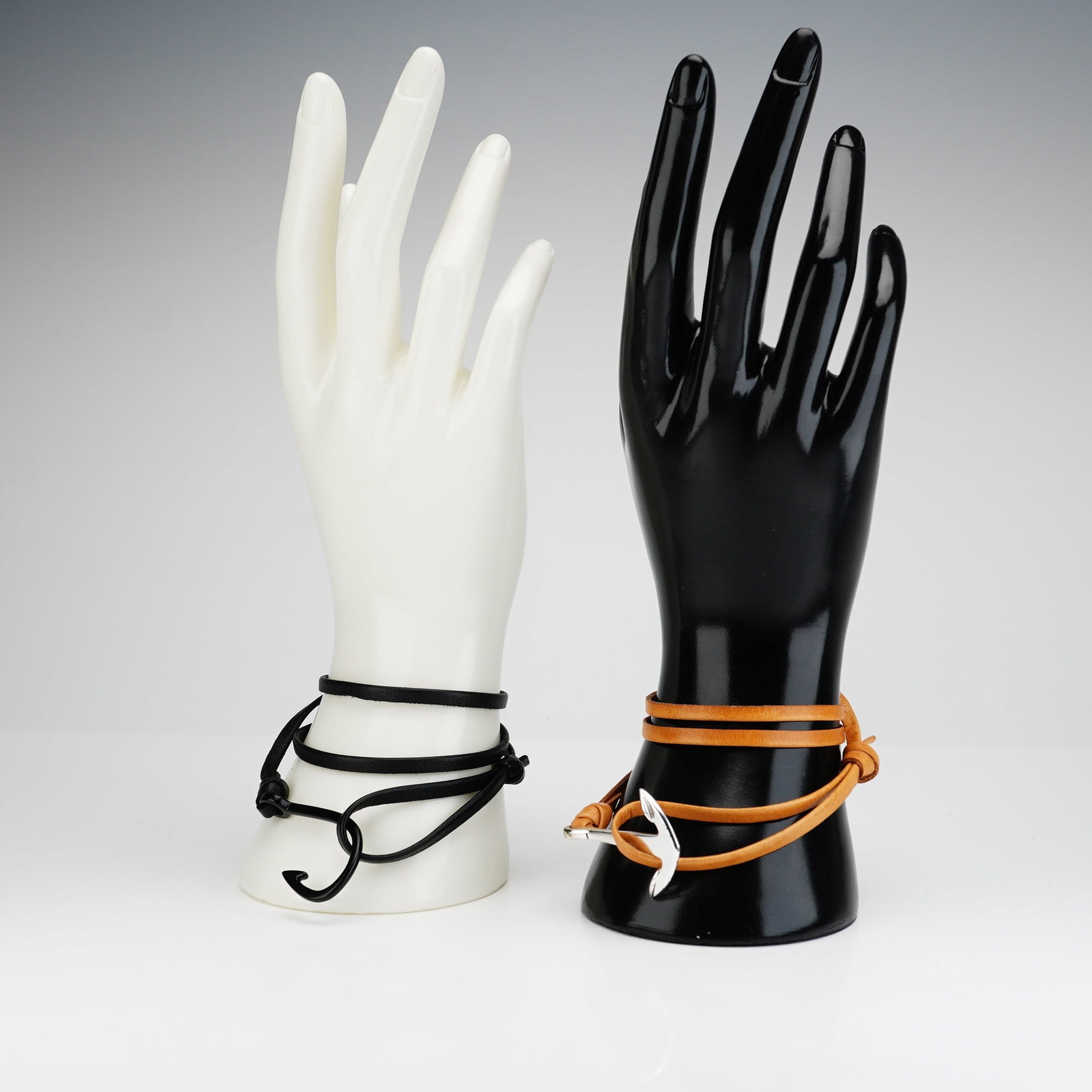 2pc Miansai Italian Leather Anchor and Hook Bracelets: Two adjustable black and brown bracelets crafted from Italian cowhide leather, each with a stainless steel anchor/hook component, one in silver-tone and the other in black-tone. Each is marked Miansai