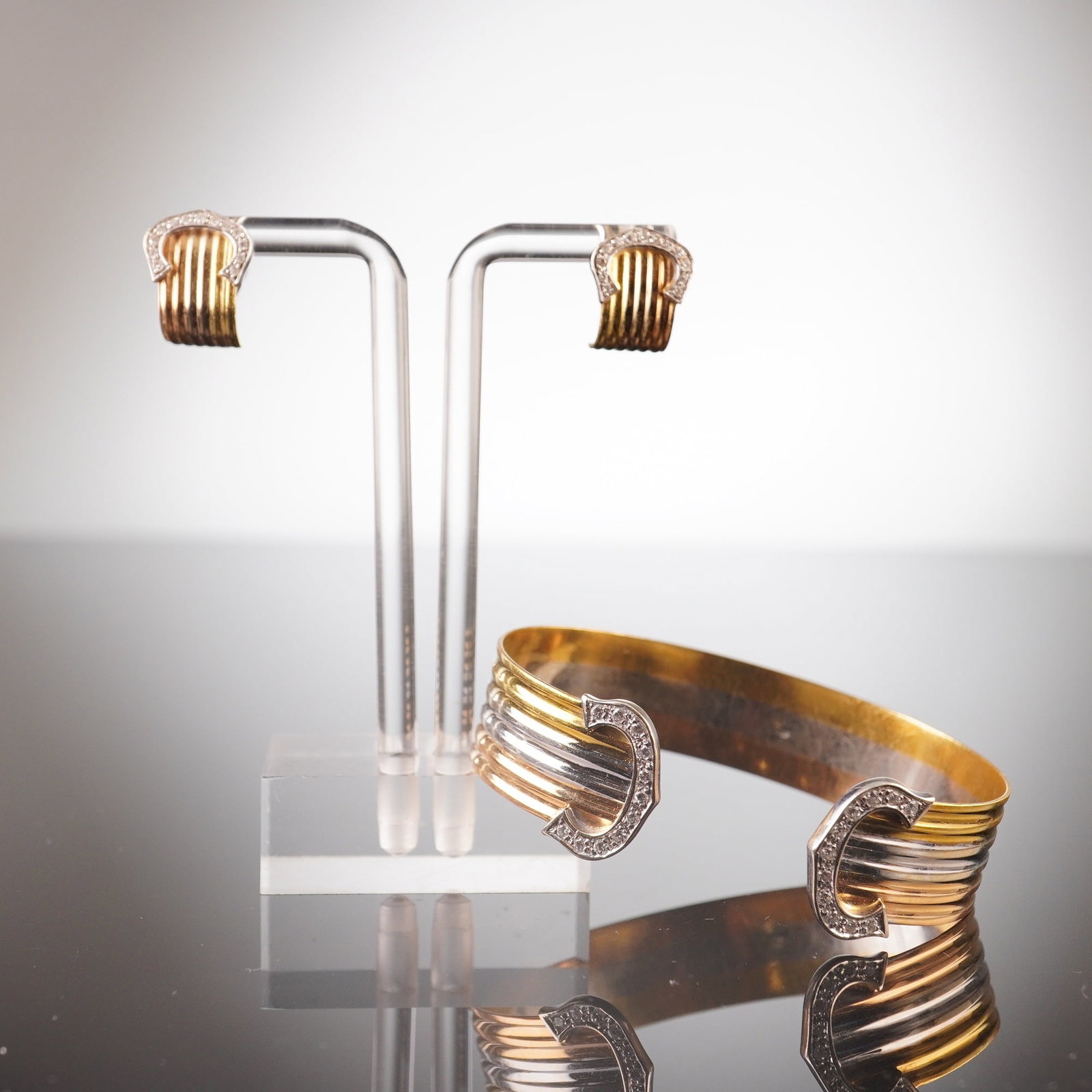 18K Tri-Color Gold Diamond Double C Open Cuff Bracelet and Earrings: This open cuff bracelet is crafted from yellow, white, and rose gold, featuring C's on each end that are set with diamonds. It comes with a pair of matching earrings in yellow and white gold, each wit