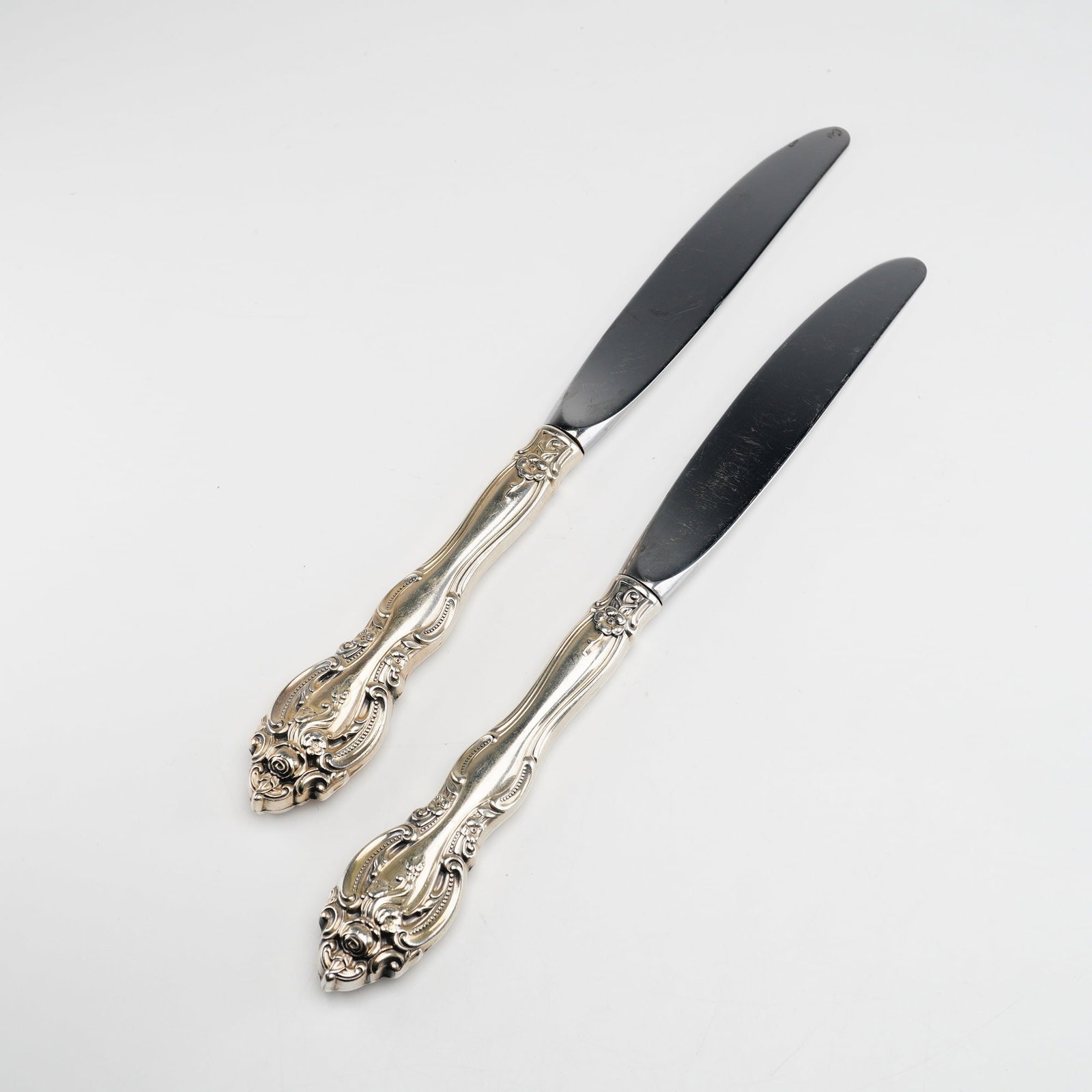 2pc Gorham Sterling Silver and Stainless Steel Dinner Knives, La Scala: A pair of dinner or place knives featuring sterling silver handles and stainless steel blades, manufactured by the Gorham Manufacturing Company of Providence, Rhode Island. The handles are decorated i