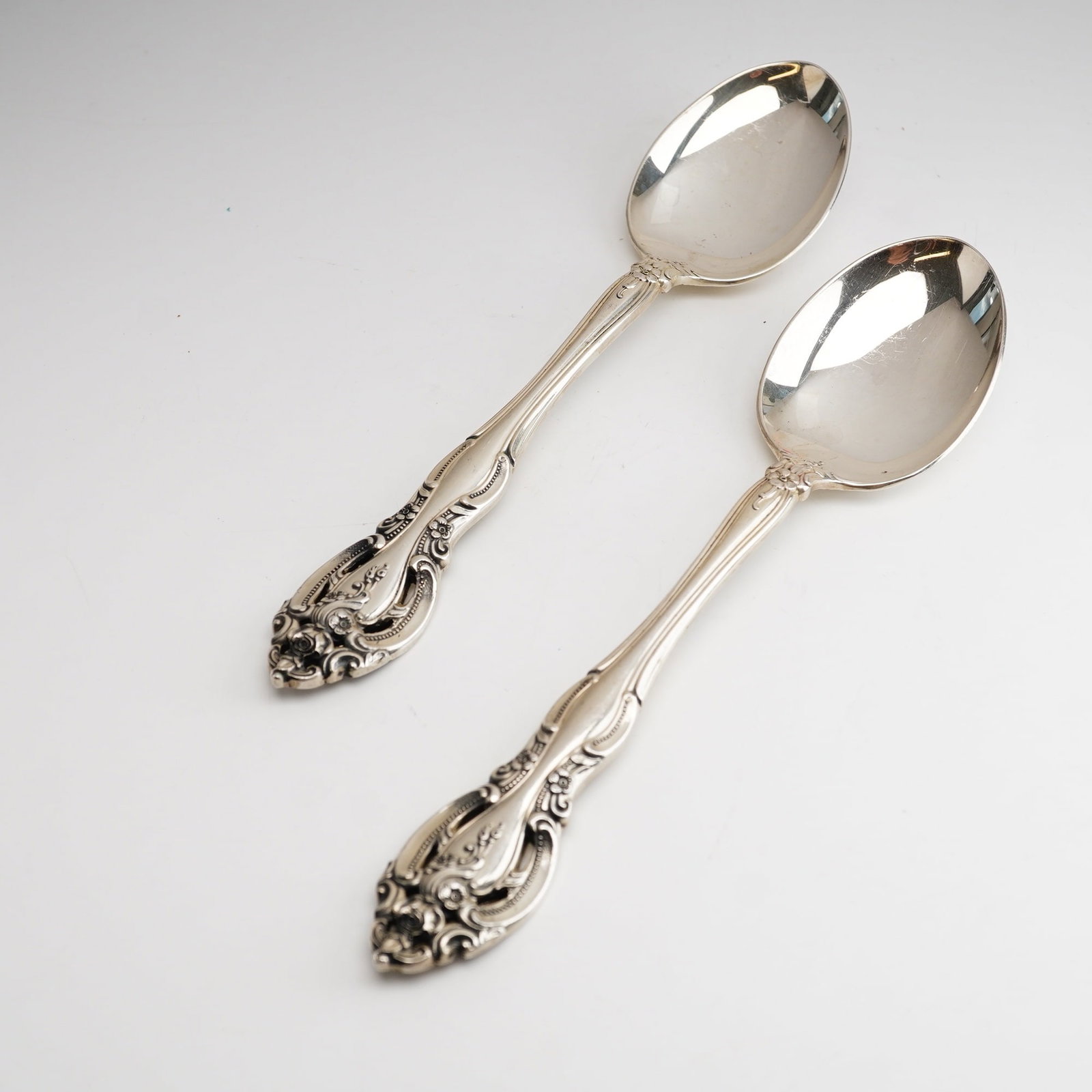 2pc Gorham Sterling Silver Oval Soup Spoons, La Scala: Ornate Rococo-style design featuring scrolling edges, shell motifs, and floral sprays including roses. The handles have a flared end with a central floral motif and do not contain any monograms. The b