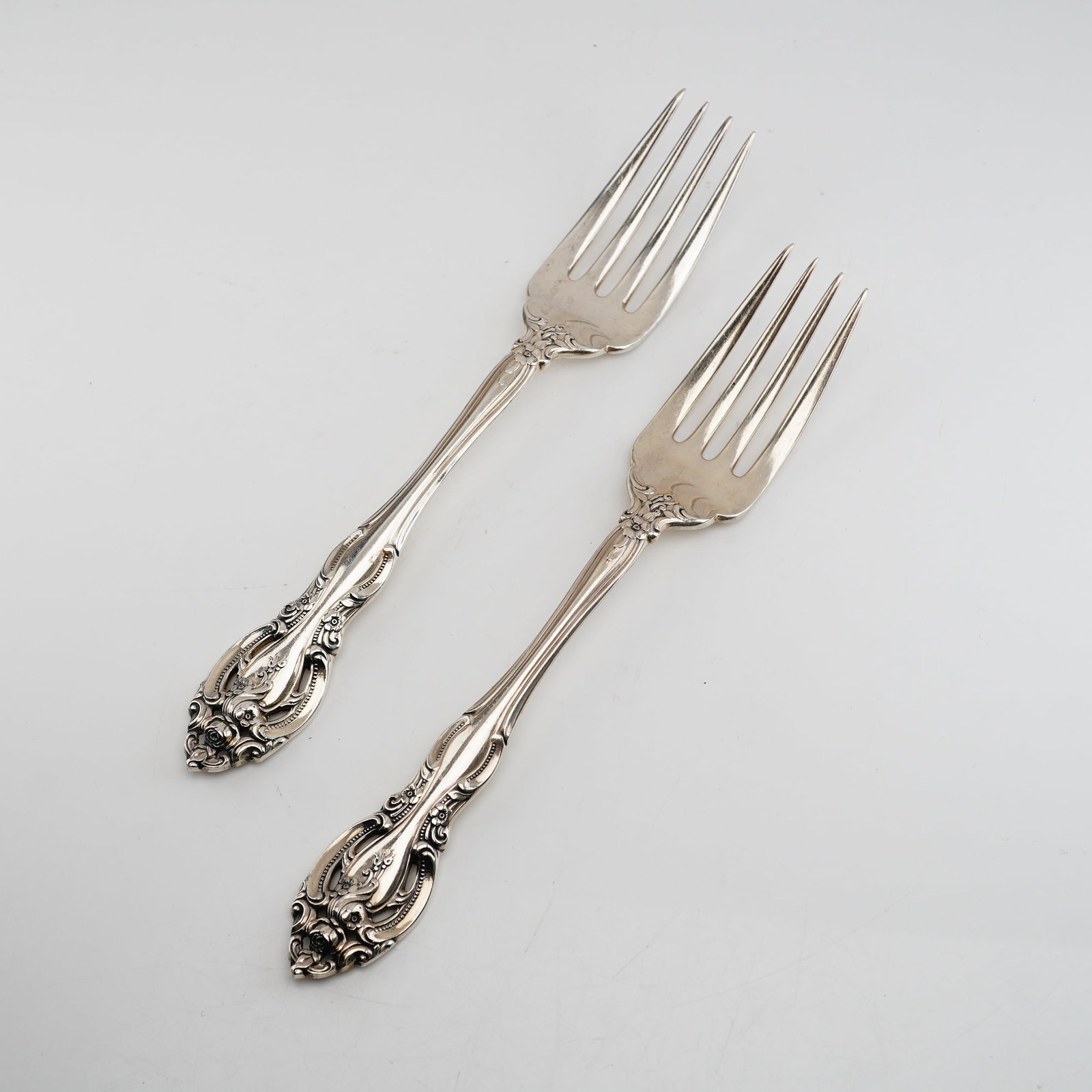2pc Gorham Sterling Silver Salad Forks, La Scala: The pattern is characterized by its ornate Rococo-revival aesthetic, featuring deeply embossed scrolls, floral clusters, and distinctive openwork piercing integrated into the handle terminals. The rev