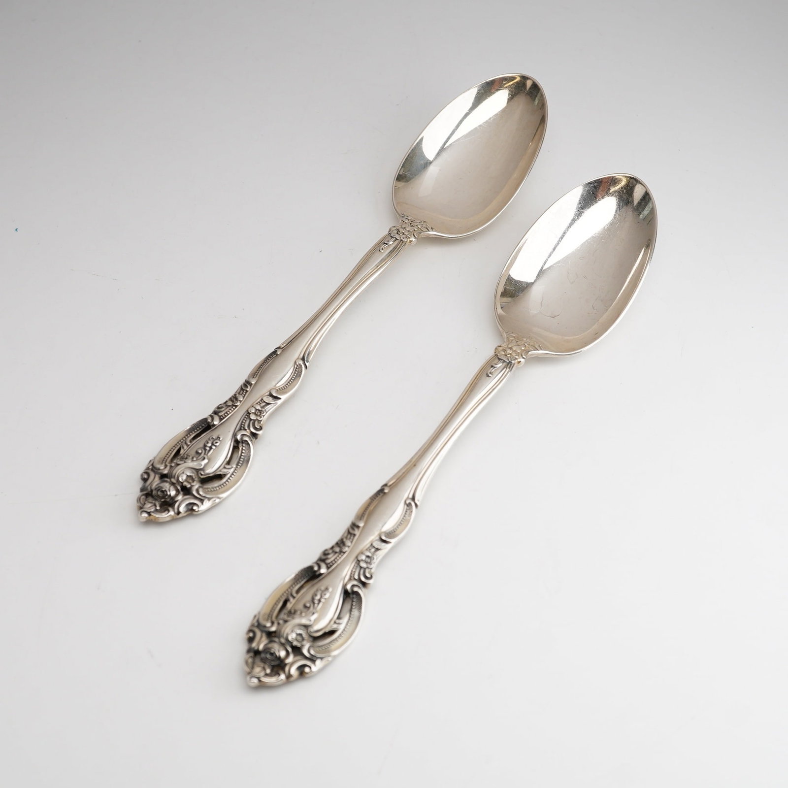 2pc Gorham Sterling Silver Teaspoon, La Scala: The design features a heavy Rococo Revival influence with intricate pierced handles, floral blossoms, and scrolling acanthus leaves. The reverse of each handle stem is struck with the official Gorham 