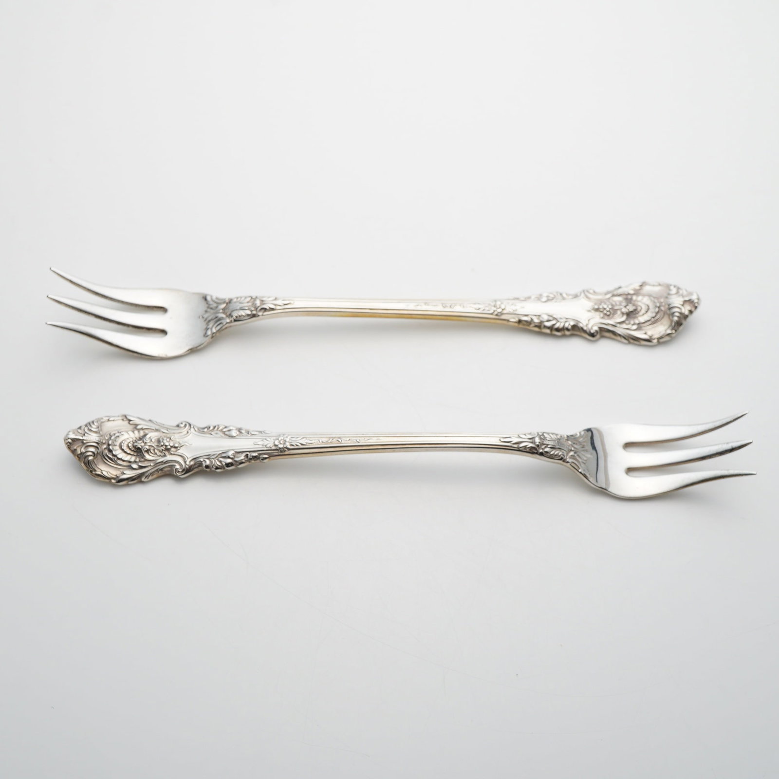 A Pair of Wallace Sterling Silver Cocktail Forks in the Sir Christopher Pattern: A pair of sterling silver cocktail forks manufactured by Wallace Silversmiths in the Sir Christopher pattern. Introduced in 1936, this pattern features a Renaissance-revival style characterized by orn
