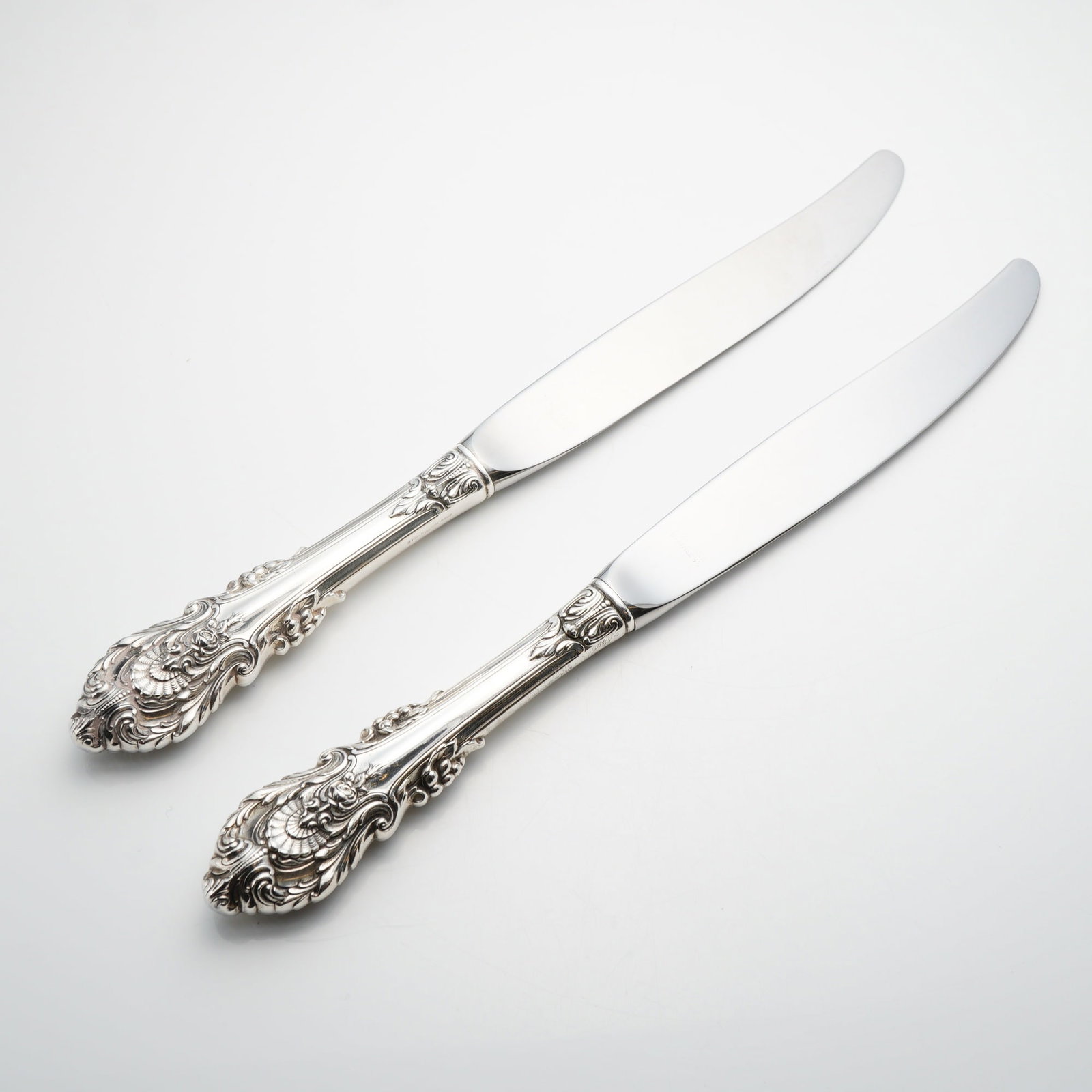 A Pair of Wallace Sterling Silver Dinner Knives in the Sir Christopher Pattern: A pair of sterling silver handled dinner knives manufactured by Wallace Silversmiths in the Sir Christopher pattern. First introduced in 1936 and designed by William S. Warren, the Sir Christopher pat