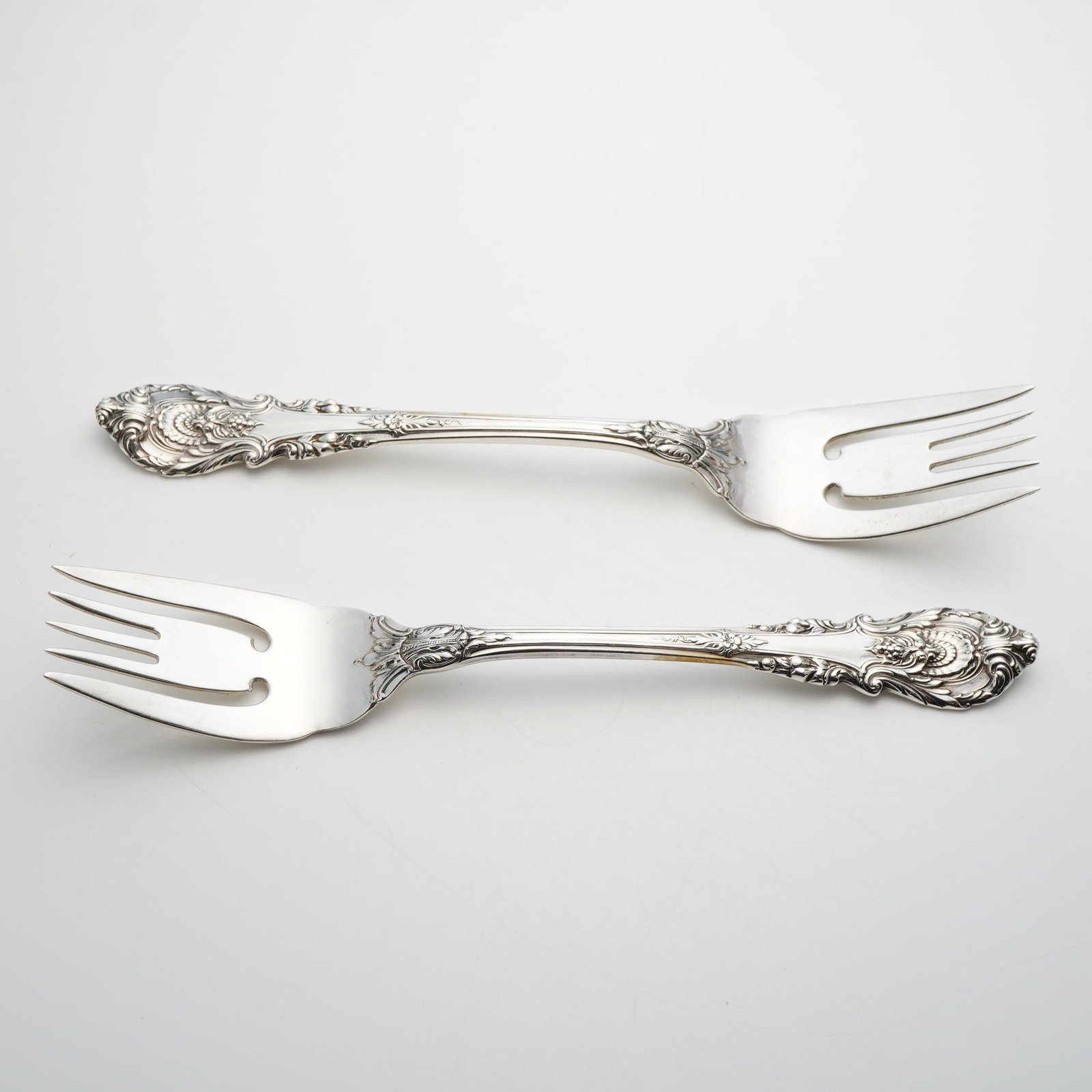 A Pair of Wallace Sterling Silver Salad Forks in the Sir Christopher Pattern: A pair of solid sterling silver salad forks manufactured by Wallace Silversmiths in the Sir Christopher pattern. This pattern, designed by William S. Warren and first introduced in 1936, is inspired b