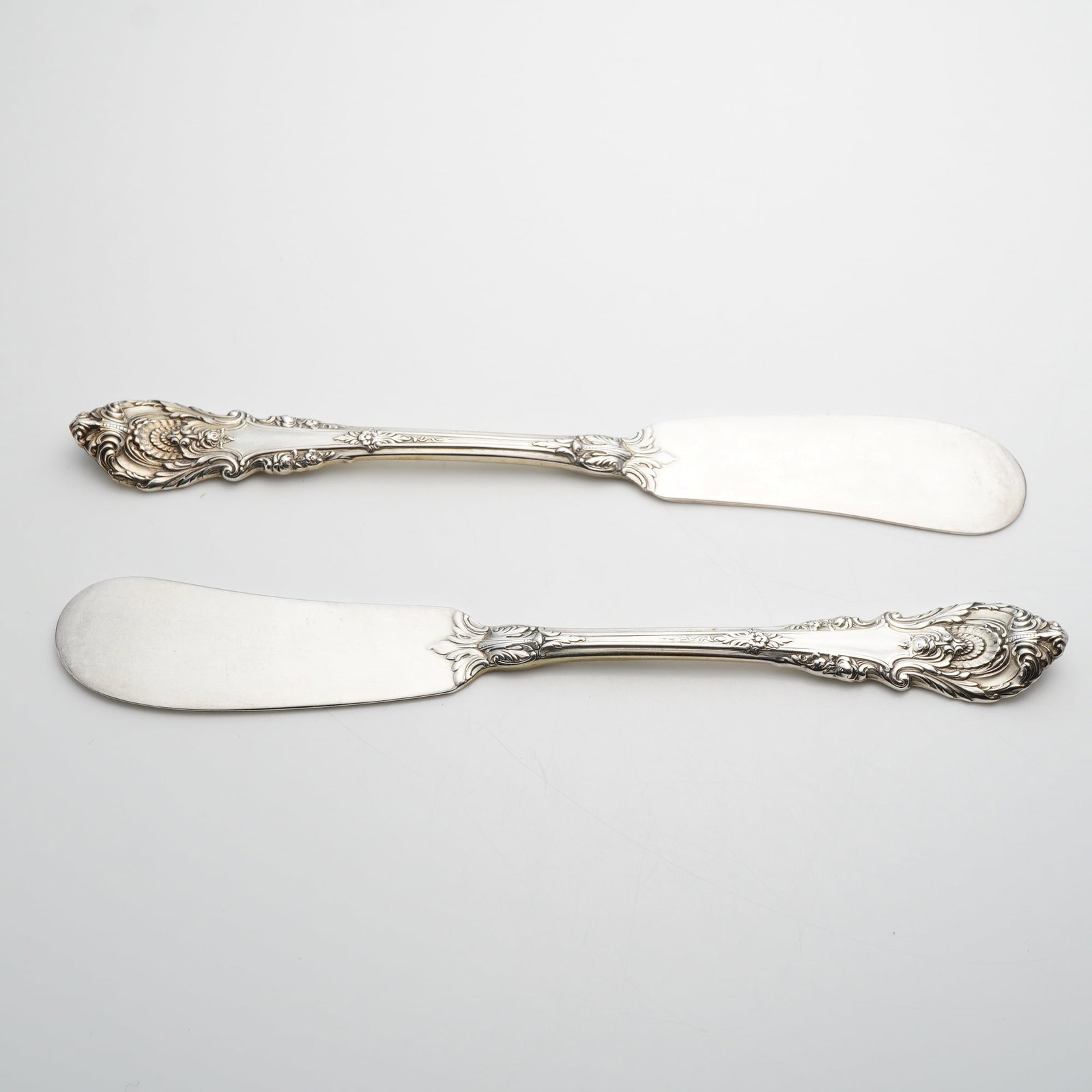 A Pair of Wallace Sterling Silver Sir Christopher Pattern Flat Handle Butter Spreaders: This pair of flat handle butter spreaders is manufactured by Wallace Silversmiths in the Sir Christopher pattern. Each spreader features a paddle blade and is constructed from a single piece of solid 