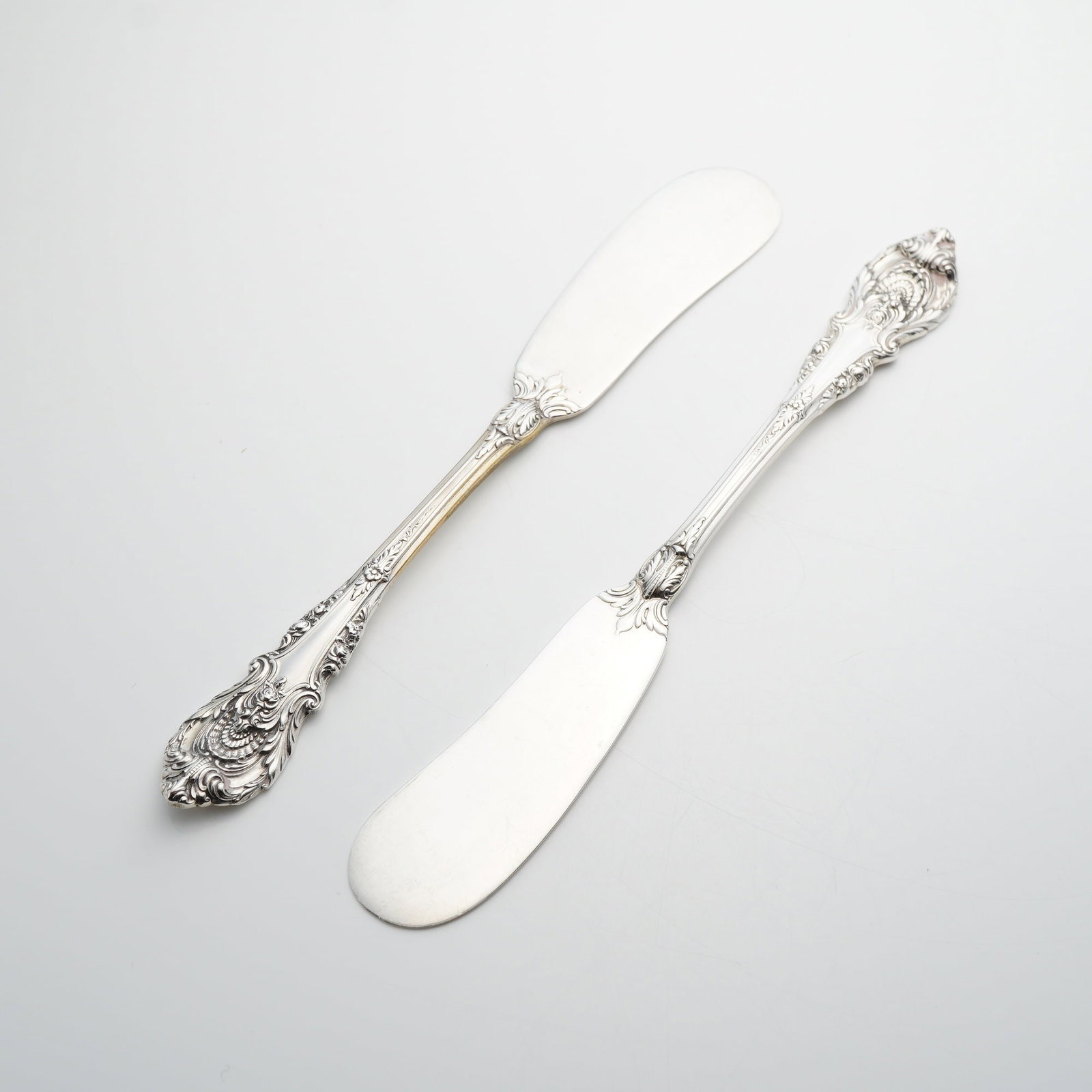 A Pair of Wallace Sterling Silver Sir Christopher Pattern Flat Handle Butter Spreaders: This is a pair of solid sterling silver flat-handle butter spreaders in the Sir Christopher pattern by Wallace Silversmiths. The Sir Christopher pattern, first introduced in 1936, is a Rococo-inspired