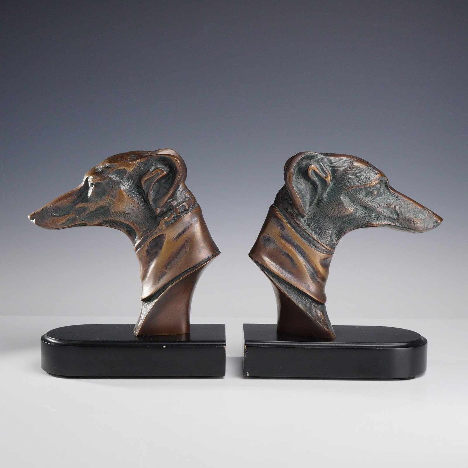 Pair of Greyhound Dog Bust Bookends: This set of two decorative bookends features cast bronze busts of greyhound or whippet dogs rendered in profile. The canine figures are depicted with detailed musculature and fine textures on the ears