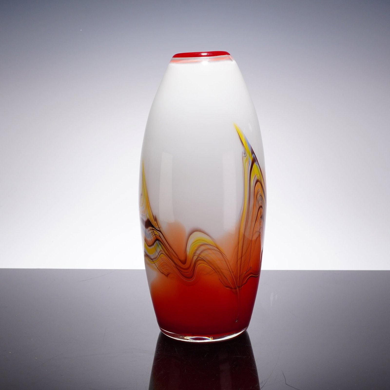 Murano Style Hand-Blown Red and White Glass Ovoid Vase: An Italian-style studio art glass vase of elongated ovoid form. This hand-blown vessel is constructed with an opaque white glass body set into a solid, vibrant red weighted base. The lower portion of 