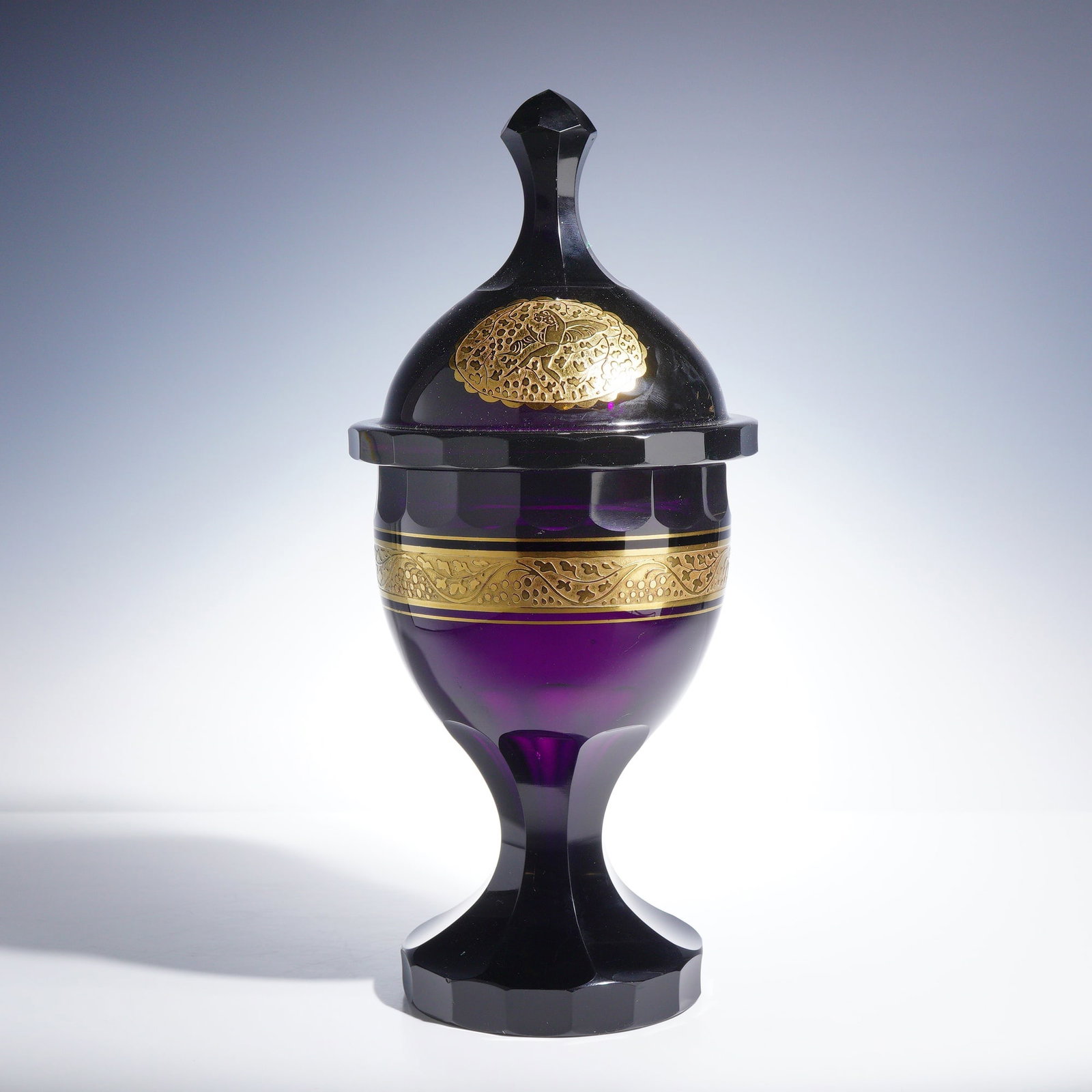 Moser Art Deco Deep Amethyst Glass Lidded Compote with Oroplastic Decoration: A Moser glass lidded compote produced in the early 20th century, crafted from deep amethyst lead glass. The piece exhibits a dark, nearly black appearance in thick sections, revealing a rich purple hu