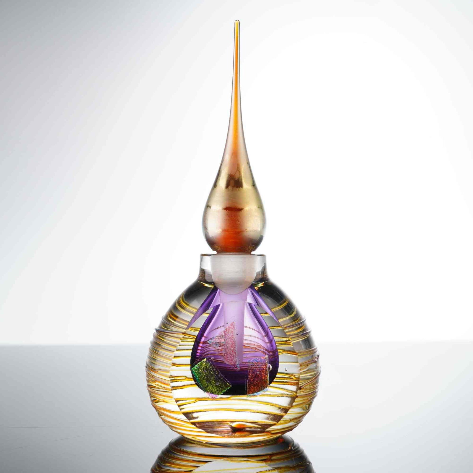 Roger Roland Studio Art Glass Perfume Bottle and Stopper: A studio art glass perfume bottle and matching stopper by artist Roger Roland, dated 1994. The piece is executed in a complex multi-layered blown glass technique featuring a bulbous clear glass body d