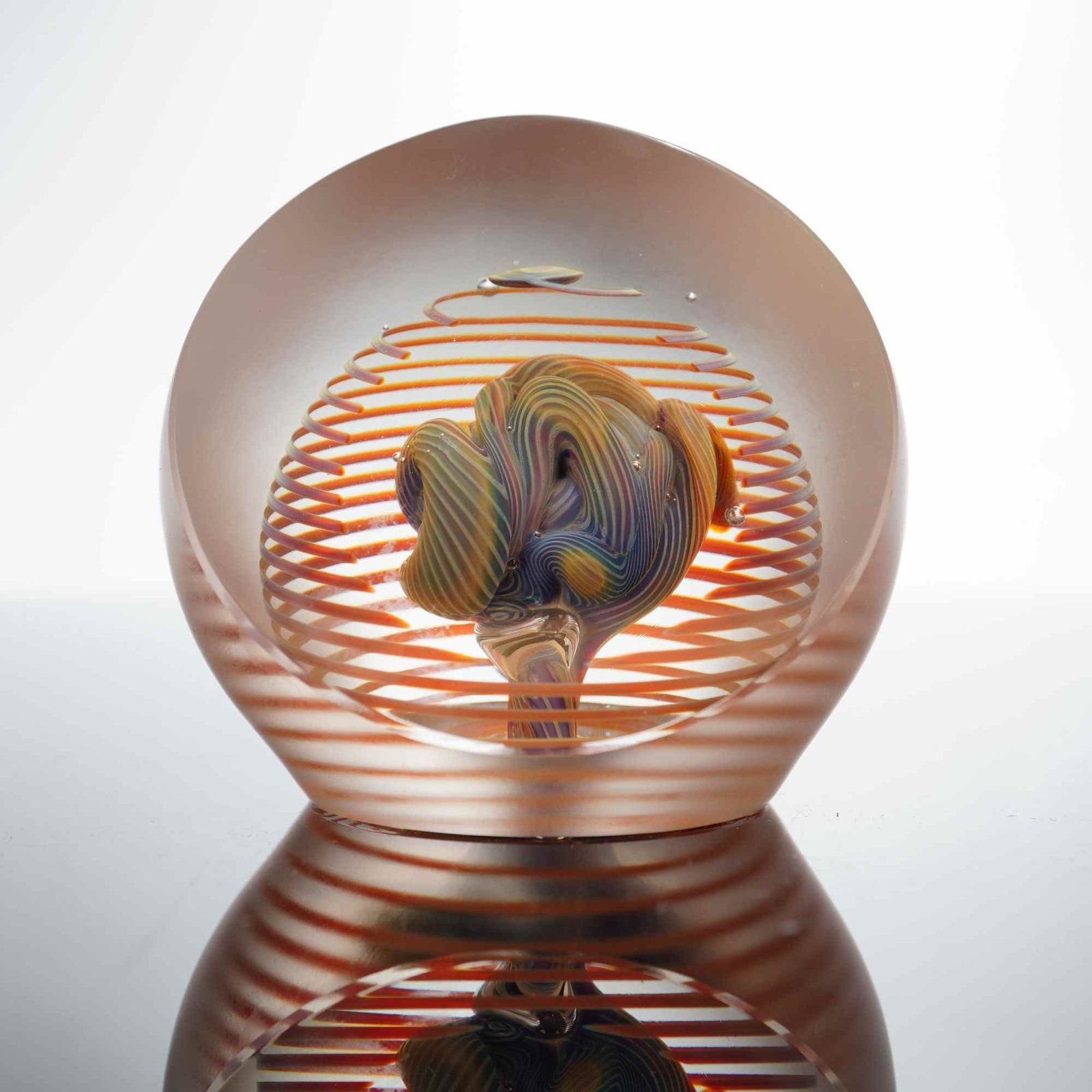 HL Marut Studio Art Glass Paperweight: A hand-blown studio art glass paperweight of spherical form by artist HL Marut. The piece features a complex, multi-colored internal core of twisted glass in shades of blue, yellow, and green. This ce