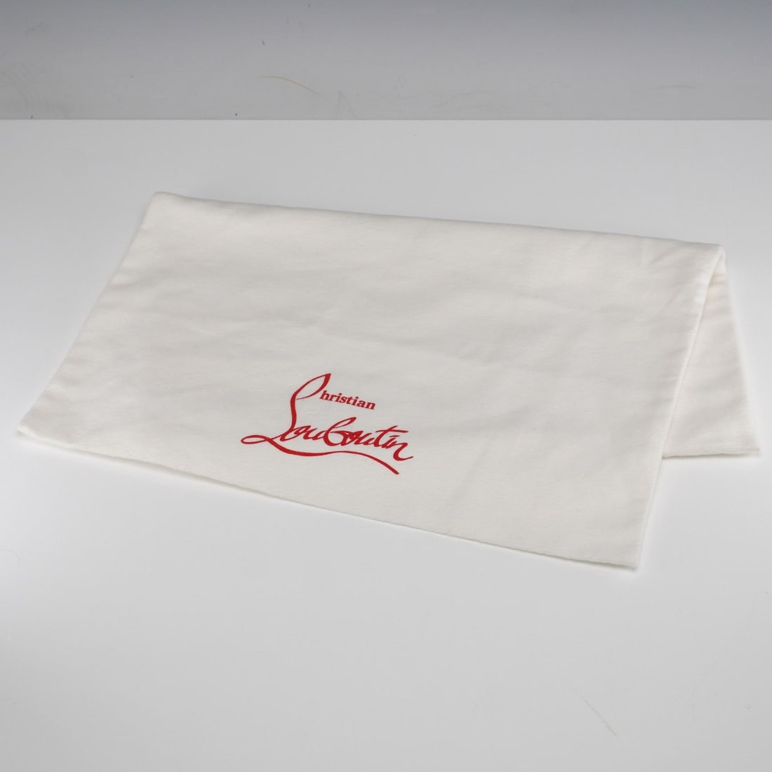 Christian Louboutin White Dust Bag: A Christian Louboutin white dust bag. This off-white, rectangular textile dust bag is made from cotton or a similar soft fabric. It features the brand name Christian Louboutin prominently printed in a