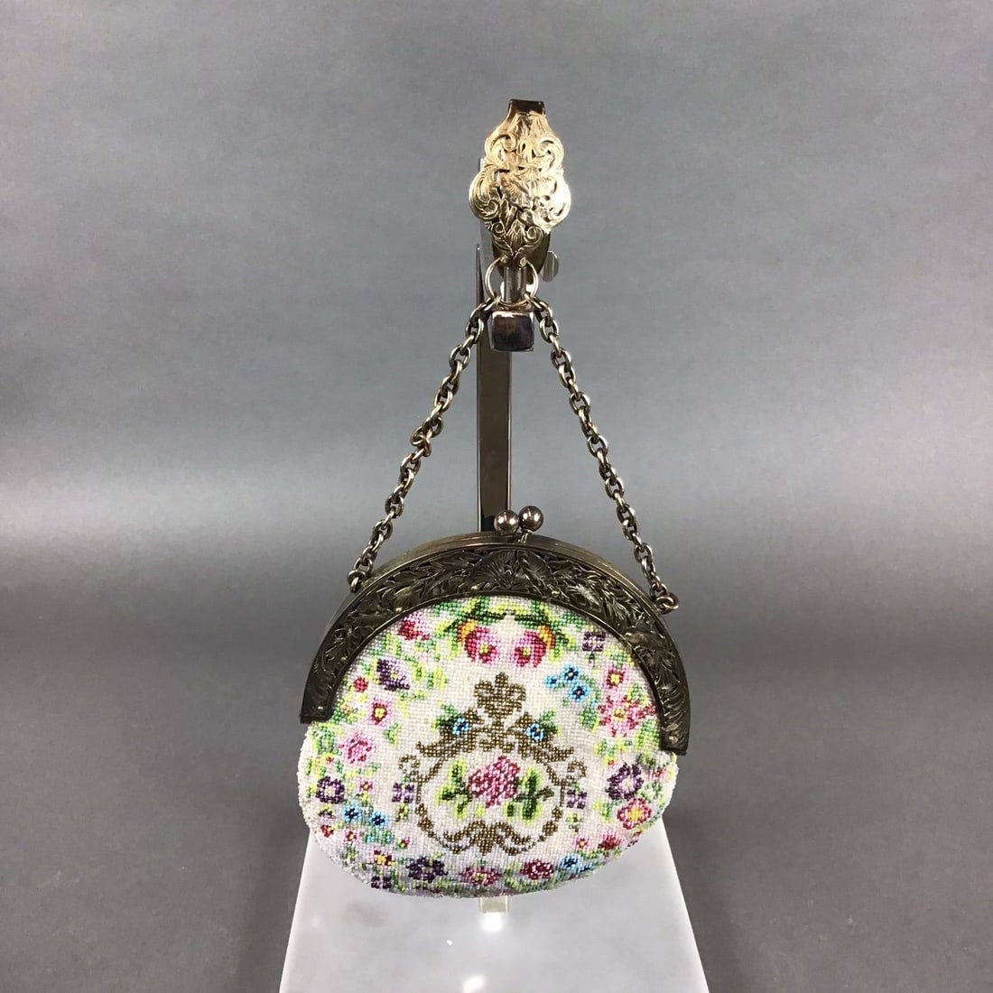 Sterling Silver and Floral Micro-Beaded Chatelaine Purse: This hand beaded coin purse is an early 20th-century accessory featuring a body of glass micro-beads on a fabric substrate. The front panel displays a multi-colored floral motif in shades of pink, ros