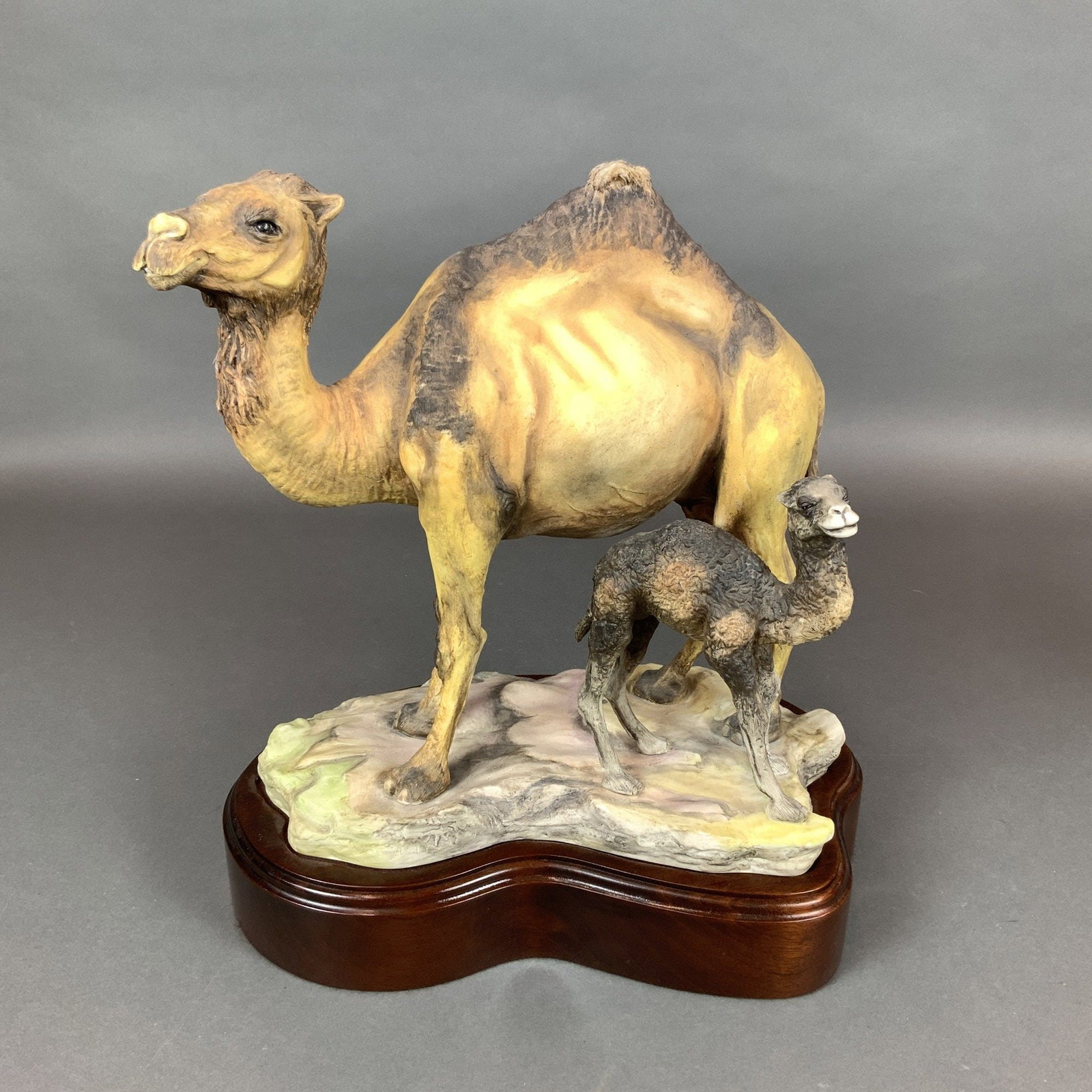Boehm Porcelain Arabian Camel with Calf Limited Edition Sculpture: A hand-painted bisque porcelain sculpture by Boehm depicting an Arabian camel with its calf. The group is part of a limited edition and includes a wooden base. The figures are rendered with fine anato