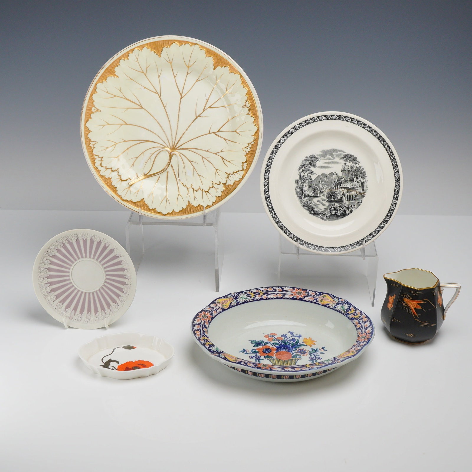6pc Wedgwood Plates, Bowls, and Creamer: This 6-piece ceramic lot features a diverse selection of English and French-style pottery, all by Wedgwood. Included is a large cream-colored bone china plate with a molded leaf design and heavy gilt 