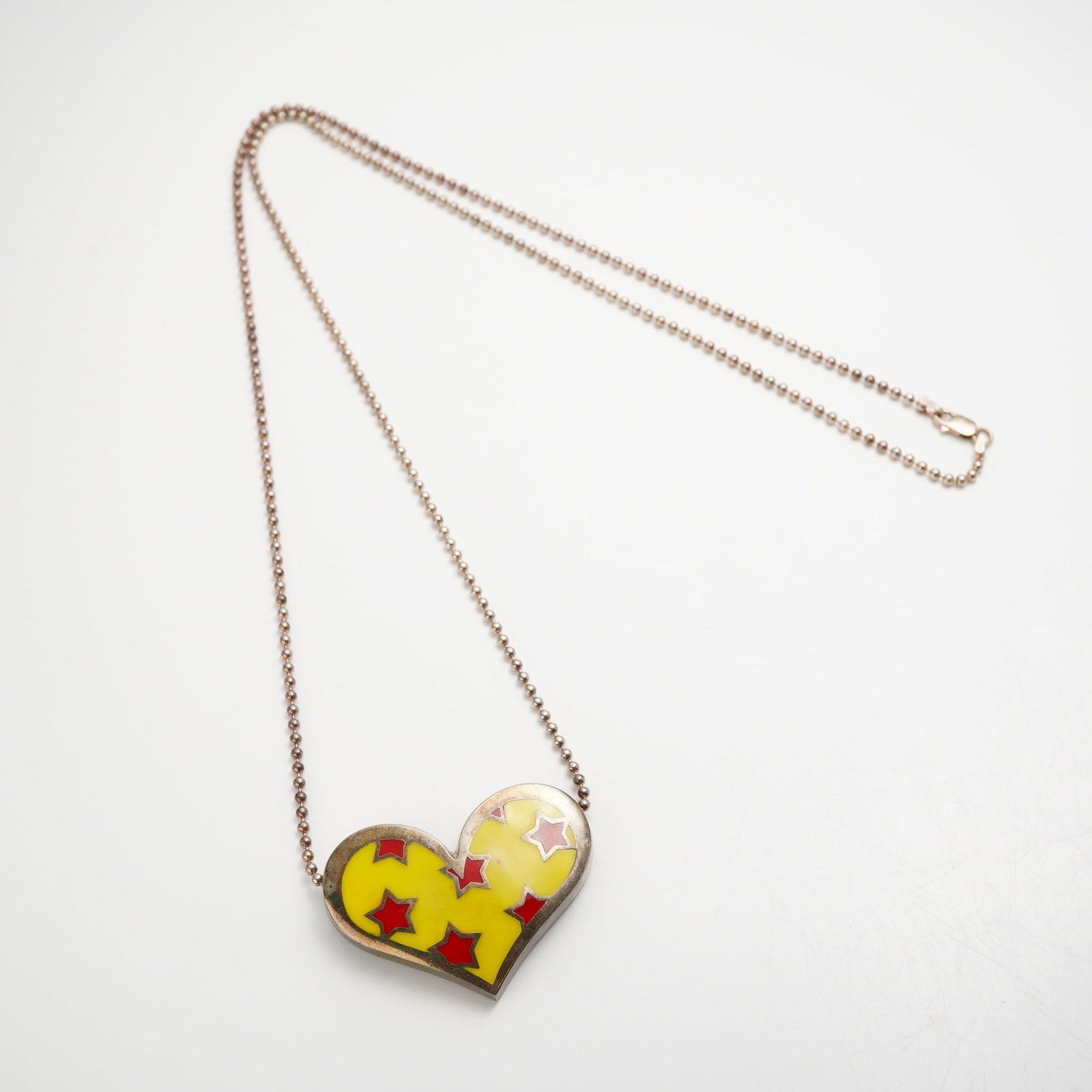 Romero Britto Sterling Silver Enamel Heart Brooch Necklace: This sterling silver necklace features a convertible heart-shaped pendant that also functions as a brooch, featuring the pop-art style of artist Romero Britto. The pendant is decorated with vibrant ye
