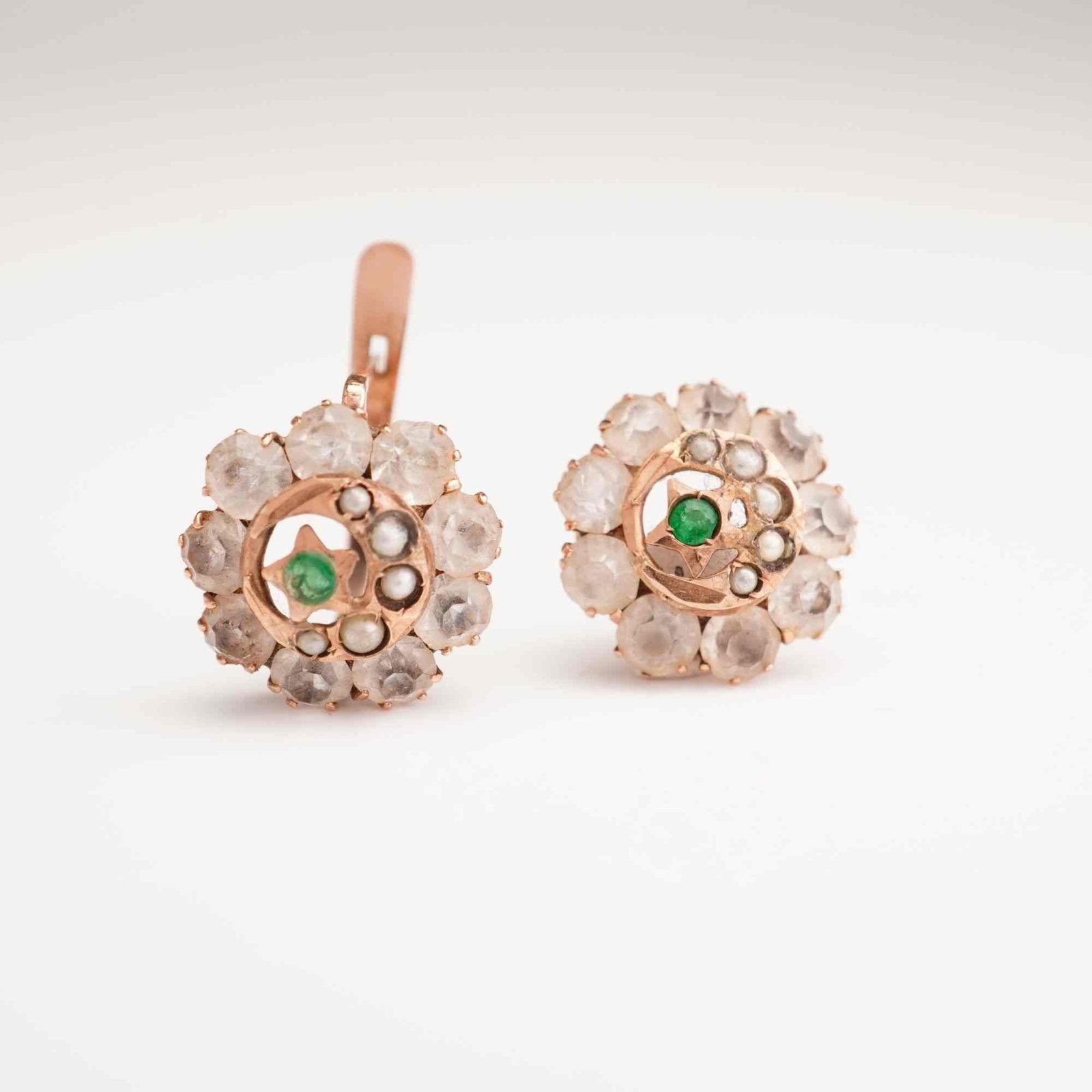 Pair of Antique 9k Rose Gold Emerald and Seed Pearl Cluster Earrings: This is a matched pair of antique cluster-style earrings crafted in 9k rose gold. Each earring features a centrally-set round-cut green emerald within a star-shaped setting. This central motif is part