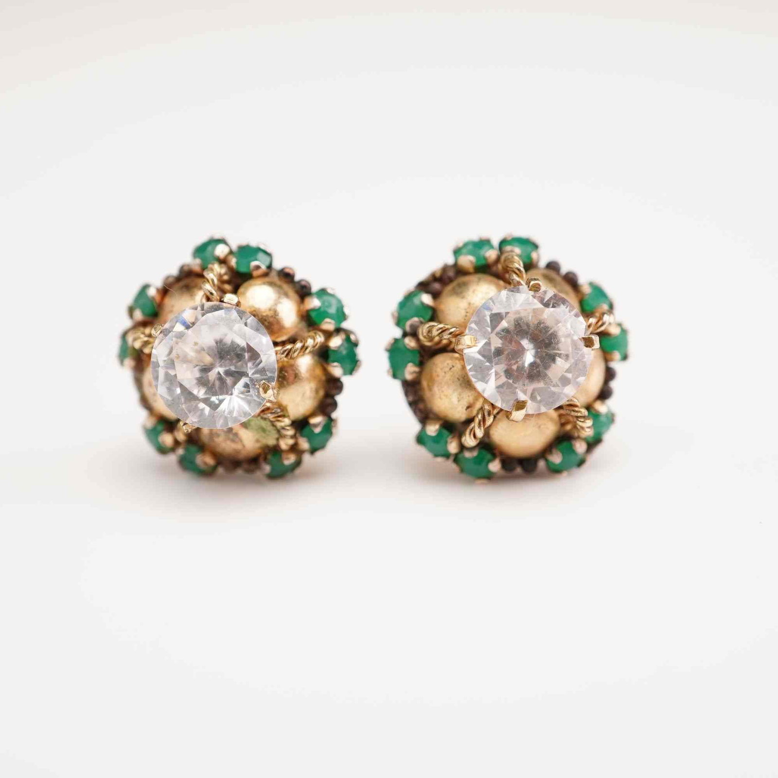 Pair of Gold-Plated Cluster Stud Earrings: A matched pair of cluster-style stud earrings. Each earring is crafted from gold-plated metal and features a prominent central, round-cut clear stone secured by a four-prong setting with twisted wire 