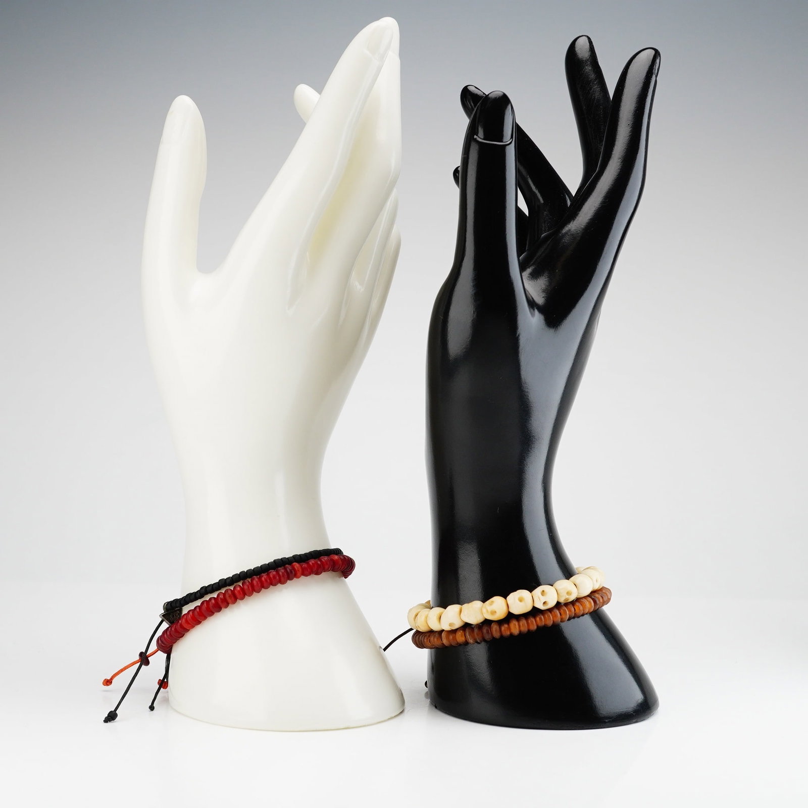 4pc Assorment of Beaded Bracelets including Carved Bone Skulls: A collection of four beaded bracelets with pull-cord closures. The bracelets feature round deep red, brown, and black beads, as well as one composed of small skulls carved from bone. Three of the brac