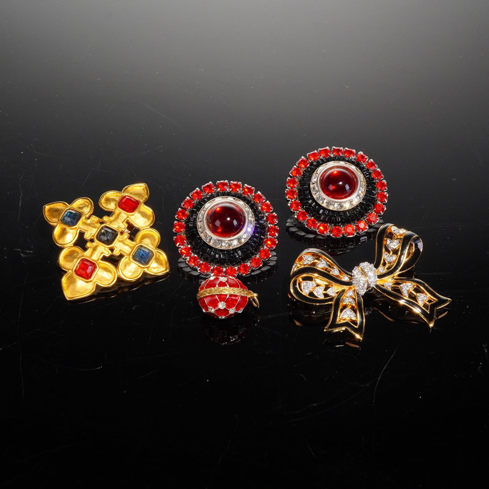 4pc Mixed Gold-Tone Costume Jewelry: A collection of late 20th-century mixed costume jewelry, which includes a highly stylized bow brooch, a pair of circular clip-on earrings, a geometric cross-form pin, and a small spherical pendant. Th