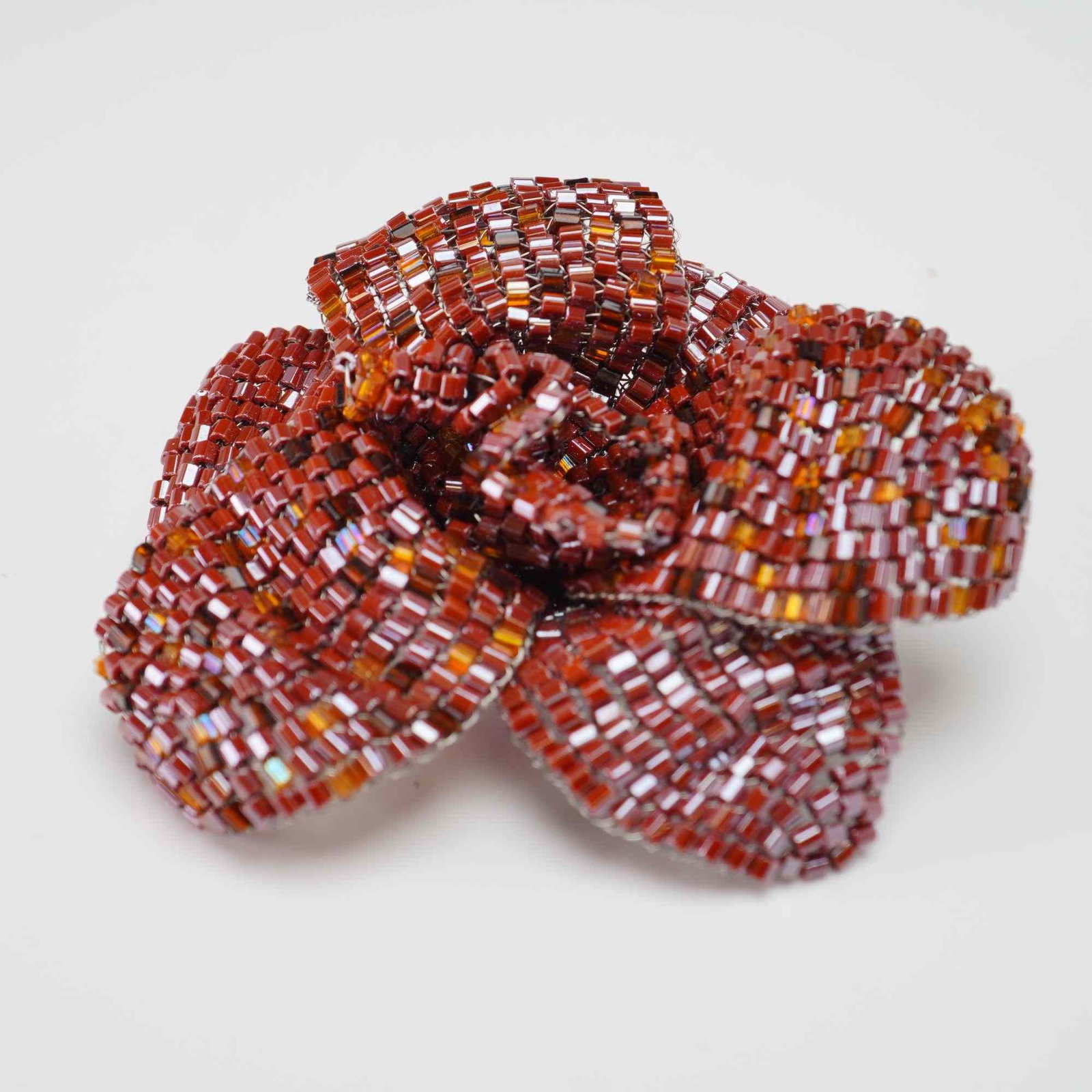 Beaded Floral Brooch with Sterling Silver Clasp: Beaded floral brooch is designed as a stylized three-dimensional flower, resembling a rose or peony. The piece is meticulously crafted from red and amber-colored glass bugle beads woven over a wire ar