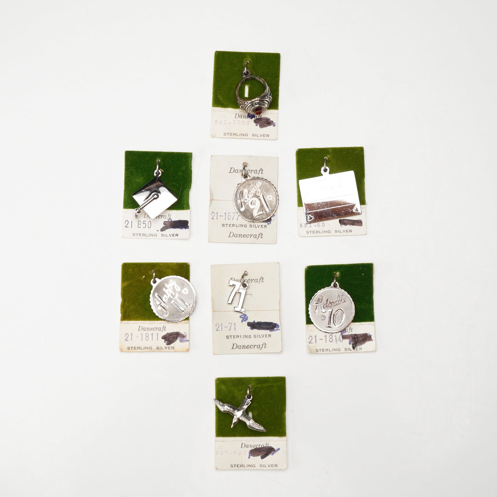8pc Danecraft Sterling Silver Charms Collection: The assortment includes seven charms and one class ring charm, most of which remain attached to their original retail display cards. The ring is a signet-style design featuring decorative shoulders an