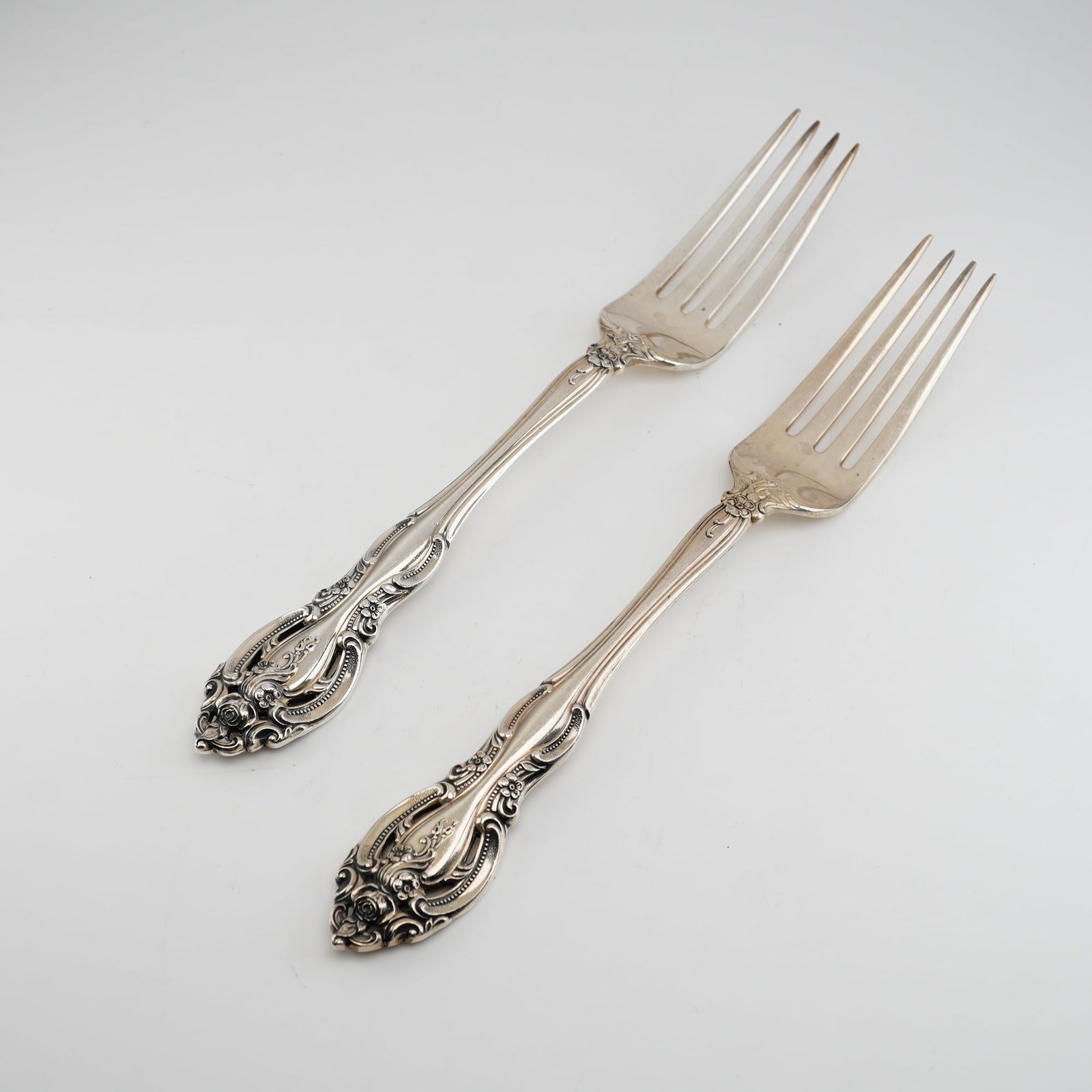 2pc Gorham Sterling Silver Dinner Forks, La Scala: Ornate Rococo-revival design. These forks feature pierced handles with exuberant scrollwork and clusters of roses and acanthus leaves. The decoration is deeply cast and extends to the reverse of the h