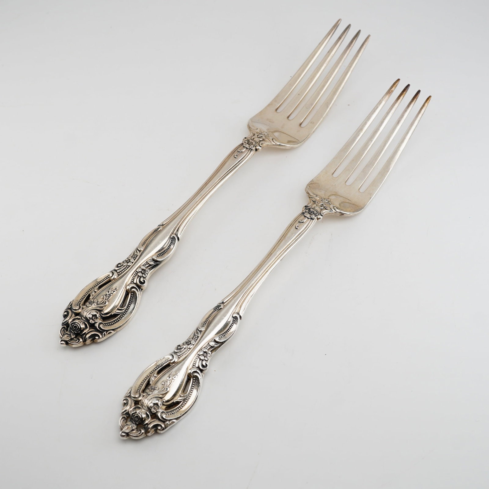 2pc Gorham Sterling Silver Dinner Forks, La Scala: The forks feature a highly ornate Rococo-revival style with deeply embossed scrollwork, shell-like motifs, and blooming rose clusters. This decorative pattern is present on both the front and back of 