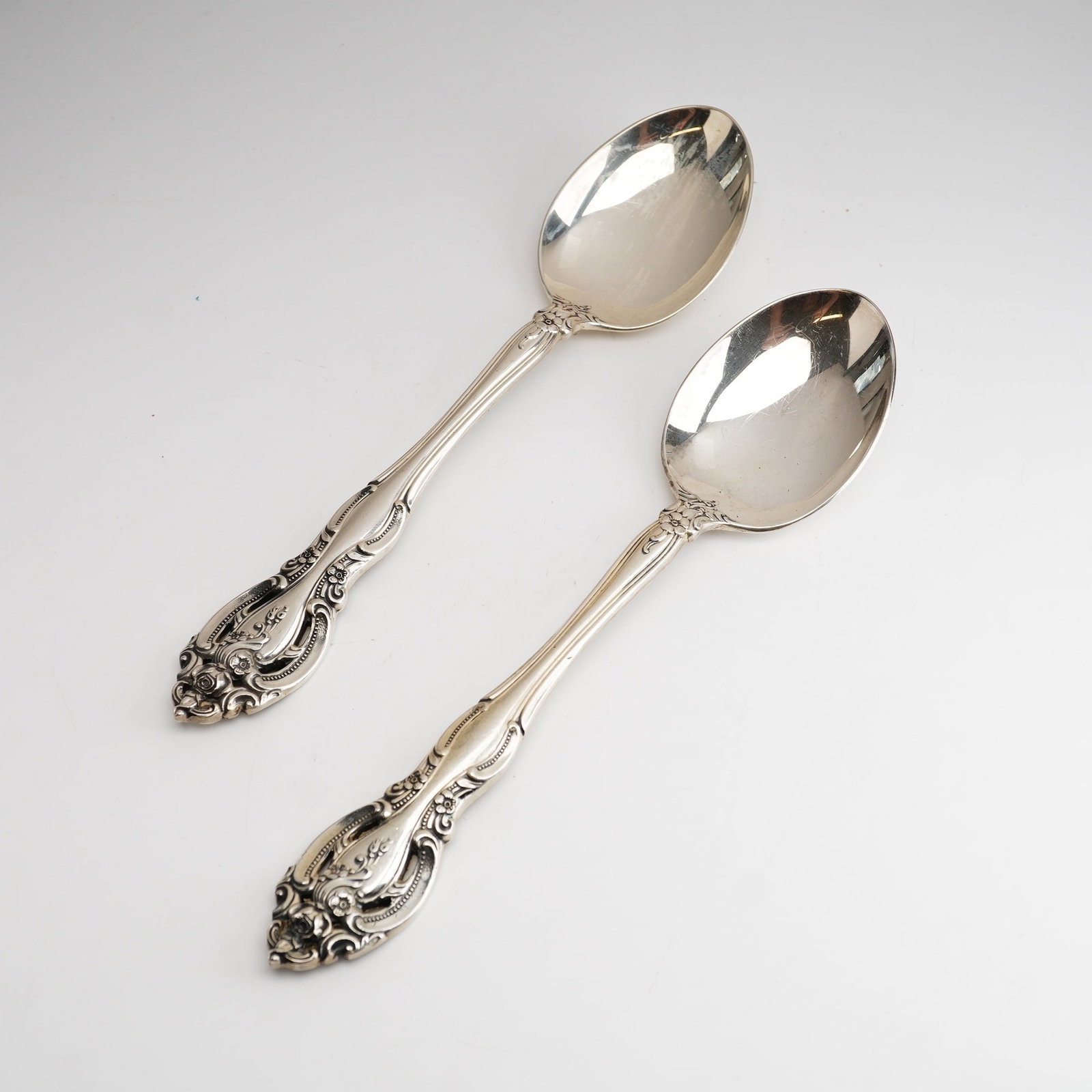 2pc Gorham Sterling Silver Oval Soup Spoons, La Scala: The ornate handles feature a scalloped, shaped form with heavy repousse floral motifs including roses and scrolling foliage. The reverse of each handle is marked with the Gorham company hallmarks: a l