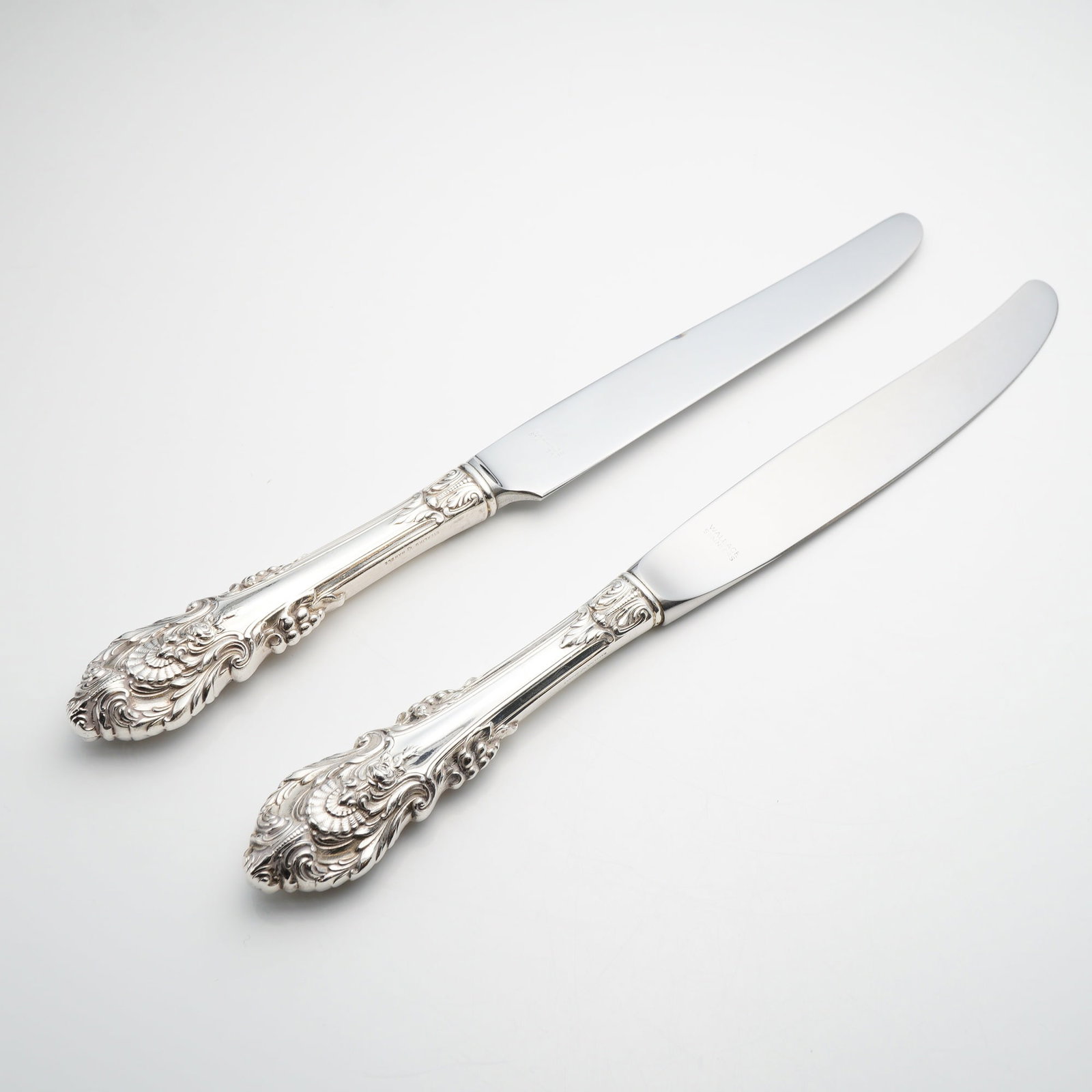 A Pair of Wallace Sir Christopher Sterling Silver Handle Dinner Knives: This pair of dinner knives is in the Sir Christopher pattern by Wallace Silversmiths. The knives feature hollow handles crafted from sterling silver paired with stainless steel blades. The Sir Christo