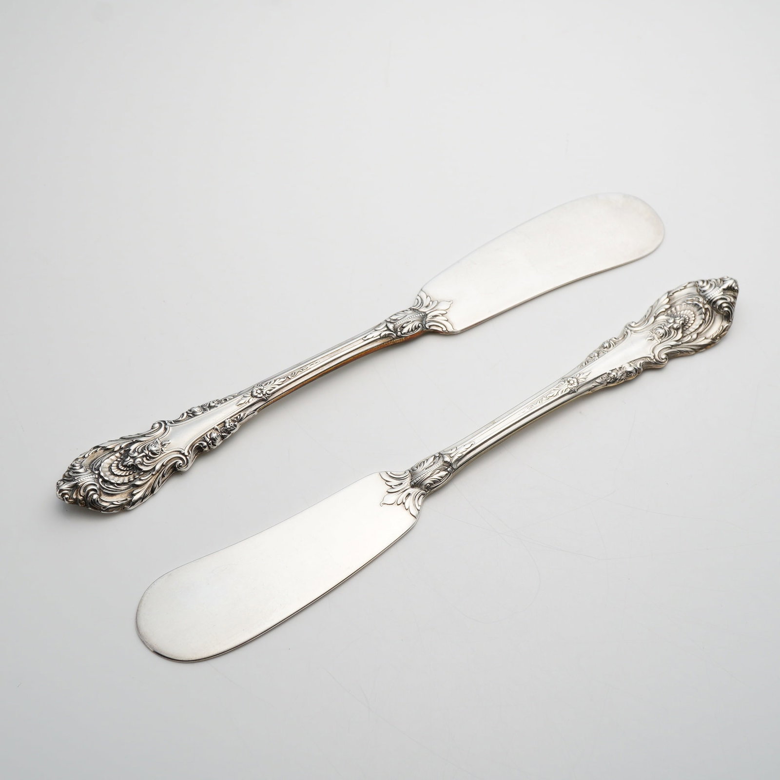 A Pair of Wallace Sterling Silver Sir Christopher Pattern Flat Handle Butter Spreaders: A pair of solid sterling silver flat handle butter spreaders produced by Wallace Silversmiths in the Sir Christopher pattern. This pattern features a classic Renaissance-inspired design with heavy rel