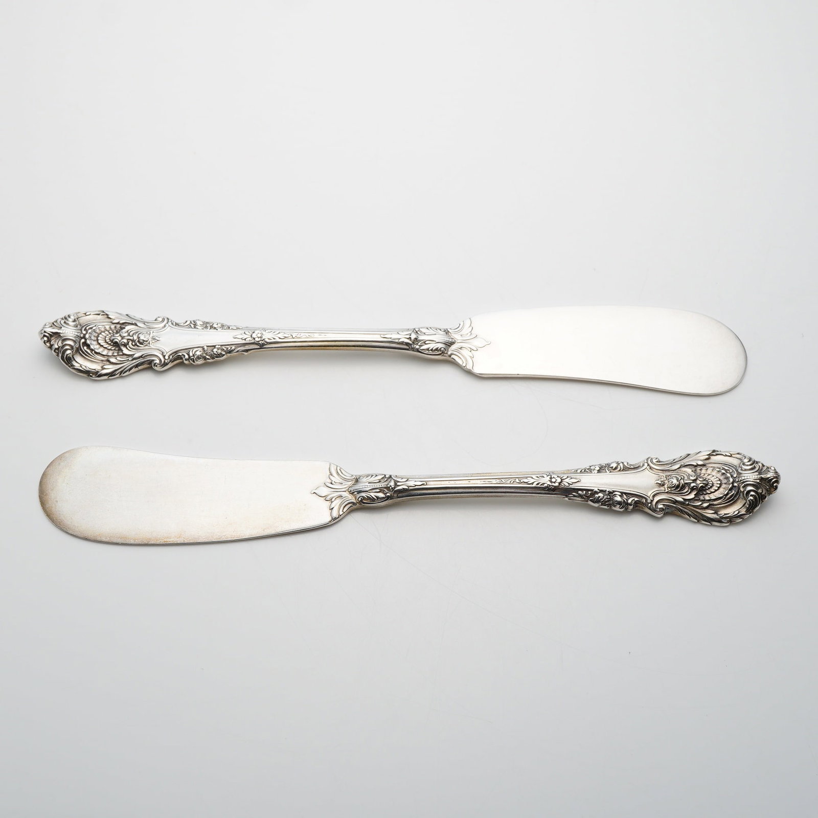 A Pair of Wallace Sterling Silver Sir Christopher Pattern Flat Handle Paddle Blade Butter Spreaders: A pair of sterling silver flat handle butter spreaders in the Sir Christopher pattern produced by Wallace Silversmiths. These pieces feature the characteristic English Renaissance-inspired design of t