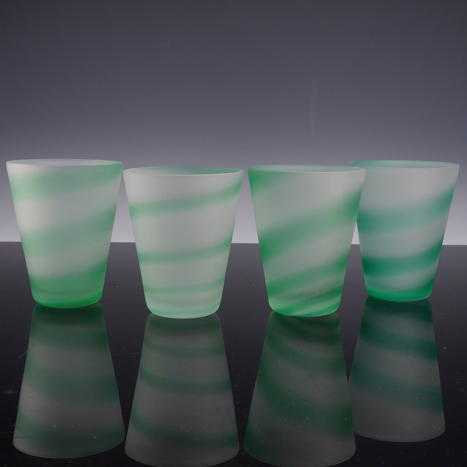 4pc Frosted Glass Tumblers with Green Spiral Stripe: A set of four frosted glass tumblers featuring a green stripe design. Each conical drinking glass is crafted from translucent glass with a satin, acid-etched finish. The primary decorative element is 