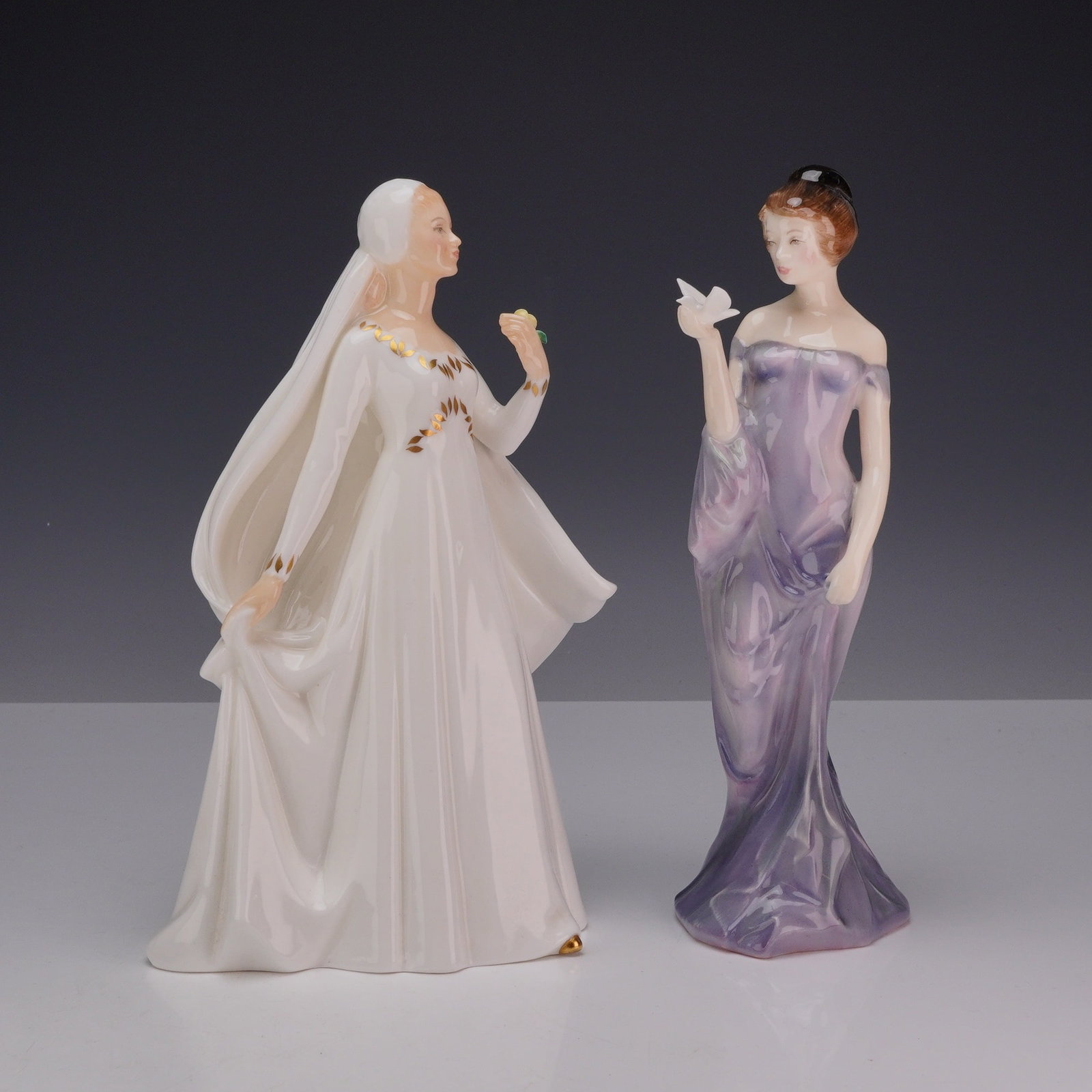 2pc Royal Doulton Bone China Figurines, Bride HN2873 and Harmony HN2824: Collection includes two Royal Doulton figures. The first, "Bride," designed by Peggy Davies, depicts a graceful bride wearing a flowing white gown accented with gilt foliate decoration to the bodice a