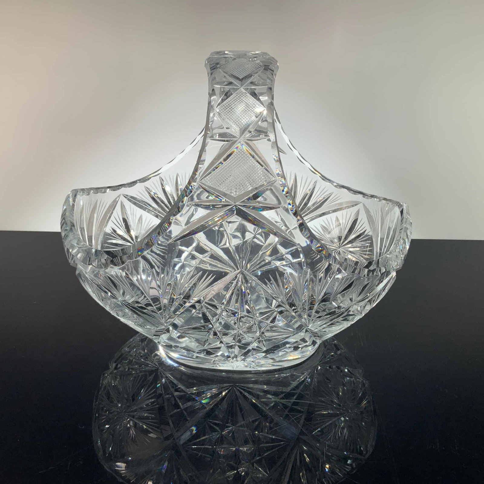 American Brilliant Period Style Hand Cut Crystal Basket with Starburst Design: This item is a large, heavy cut crystal basket crafted in the American Brilliant Period style. The piece features a fixed handle integrated into the flared sides of the body. The exterior is decorated
