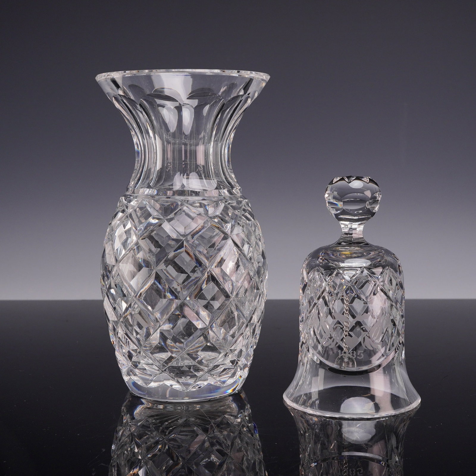 2pc Waterford Crystal Grouping Including Vase and 1985 Bell: This lot consists of two pieces of cut lead crystal manufactured by Waterford. The first item is a vase which features a bulbous pineapple form with a constricted neck and a flared rim. The body is de