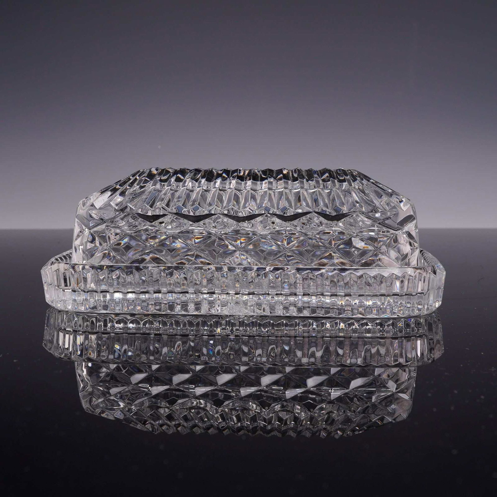 Waterford Lead Crystal Covered Butter Dish: A two-piece covered butter dish manufactured by Waterford Crystal. The set consists of a rectangular base plate and a matching domed lid. The lid features a field of deep diamond criss-cross cuts on t
