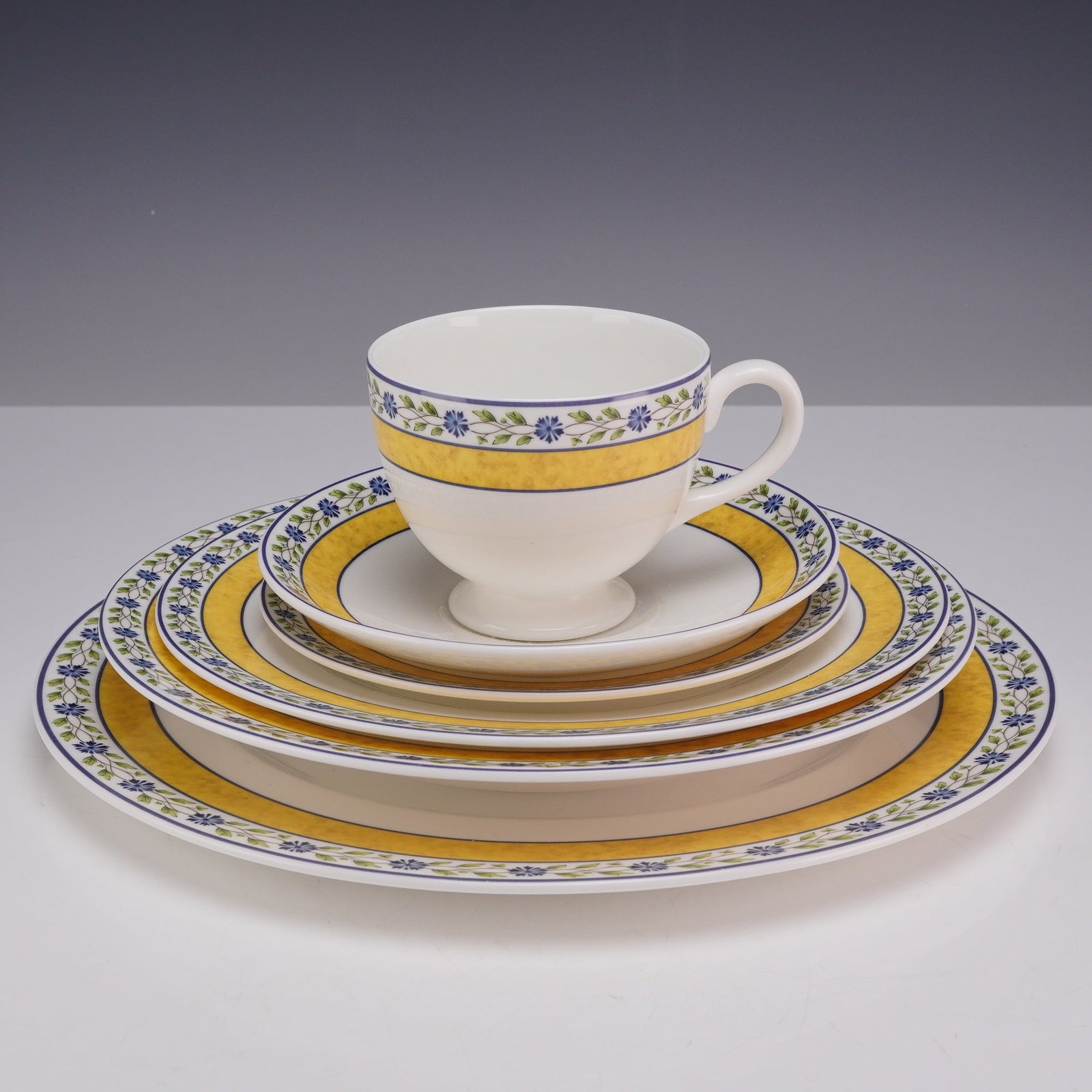 6 Piece Set of Wedgwood Bone China Plates and Teacup, Mistral: This lot features a 6-piece place setting of fine bone china manufactured by Wedgwood in the Mistral pattern, which bears a 1994 copyright. The set consists of one dinner plate, one salad plate, one b