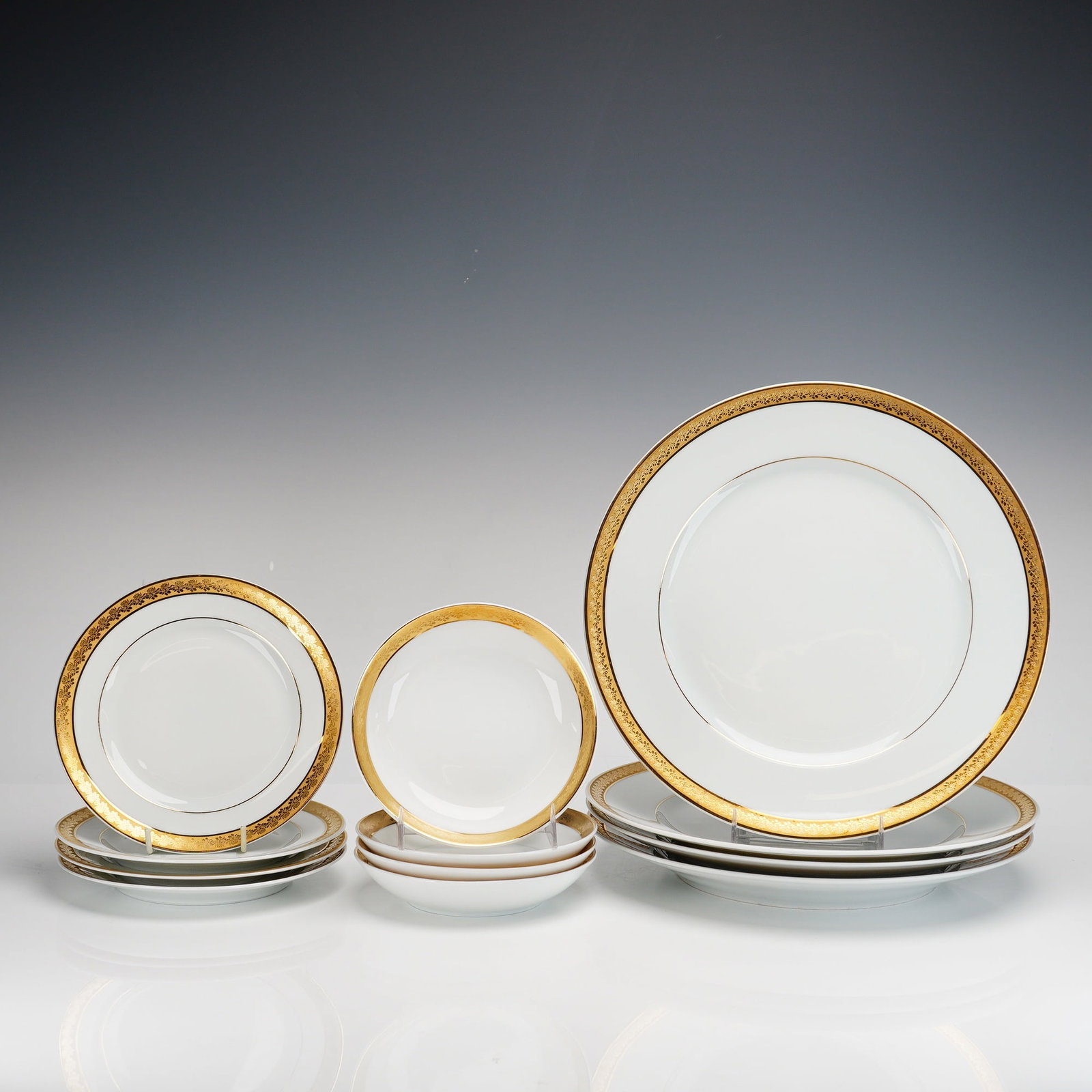 12pc Bernardaud Limoges Porcelain Dinnerware Plates and Bowls, Rhapsody Pattern: The set features the Rhapsody pattern, which is decorated with a wide, gold-encrusted rim displaying an intricate foliate motif and a fine gold line bordering the interior white ground. The collection