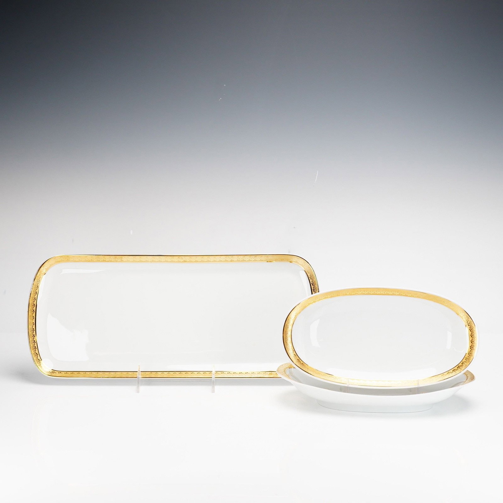 Three-Piece Bernardaud Limoges France Porcelain Serving Set, Rhapsody: The set consists of one rectangular platter with rounded corners 14.75" and two matching oval relish dishes 9.25". Each piece is crafted from white porcelain and features a wide, gold-encrusted rim de