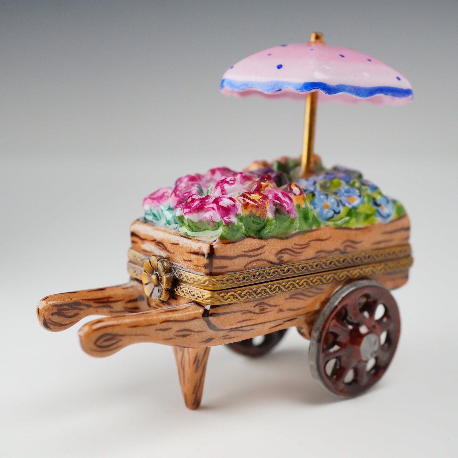 Rochard Limoges France Hand-Painted Porcelain Flower Cart Treasure Box: This hand-painted porcelain treasure box is produced in Limoges, France, for the Rochard collection. The box is modeled in the form of a flower cart or wheelbarrow. The body is decorated with a brown 