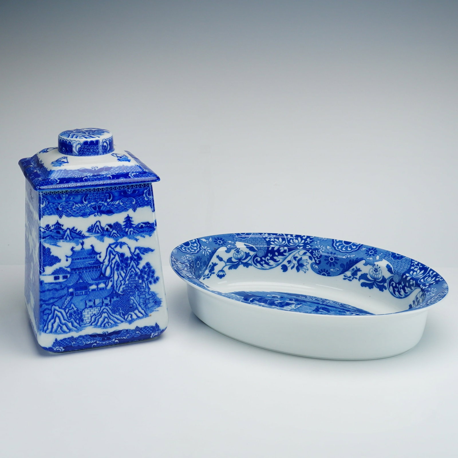 2pc Blue Willow Tea Jar and Bowl by Spode and Ringtons: This lot features two pieces of blue and white transfer-printed earthenware, consisting of a tea canister by Ringtons and a serving bowl by Spode. The square-sectioned tea jar includes a conforming li