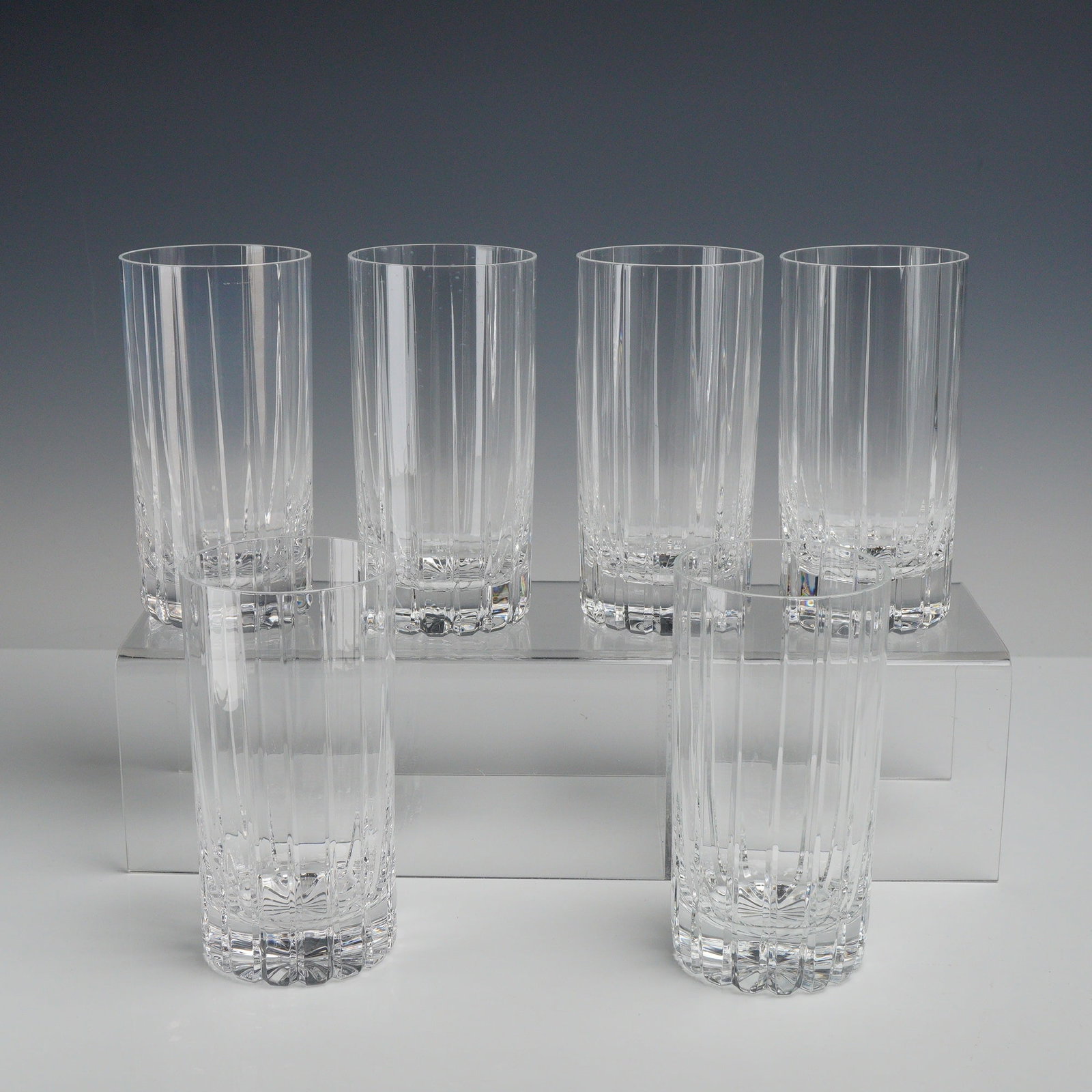 6pc Lead Crystal Cut Glass Drink Cups: This lot of 6 cut glass drink cups, styled as highball glasses or tumblers, feature a series of deep, polished vertical fluted pillar cuts that extend from the base toward a plain, polished rim. The