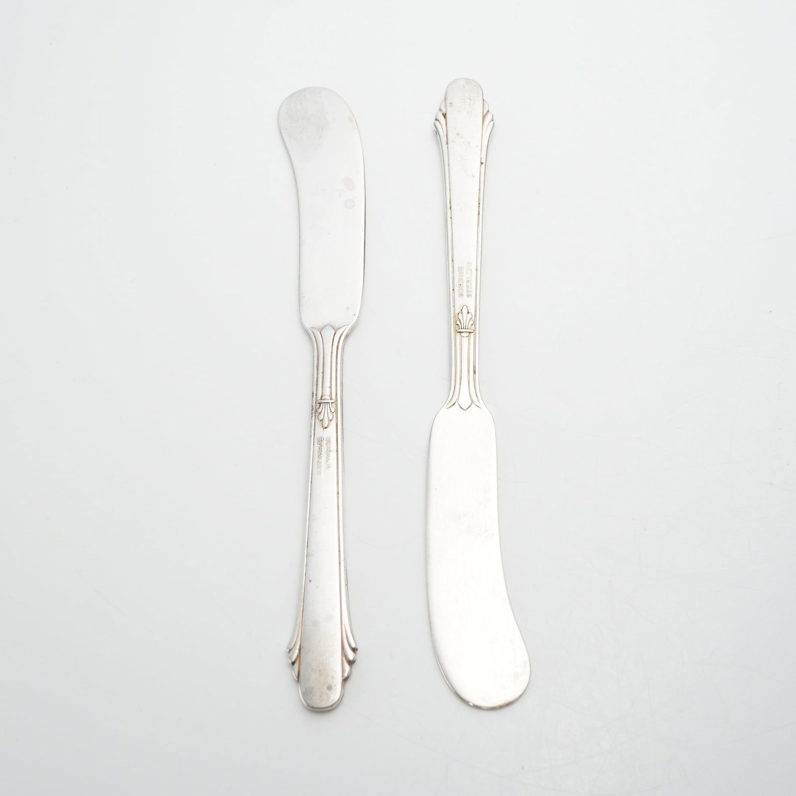 Pair of Gorham Sterling Silver Flat Handle Butter Spreader Knives: A pair of American sterling silver butter spreader knives produced by the Gorham Manufacturing Company. The pattern, introduced in 1936, features fluted vertical lines along the flat handles,