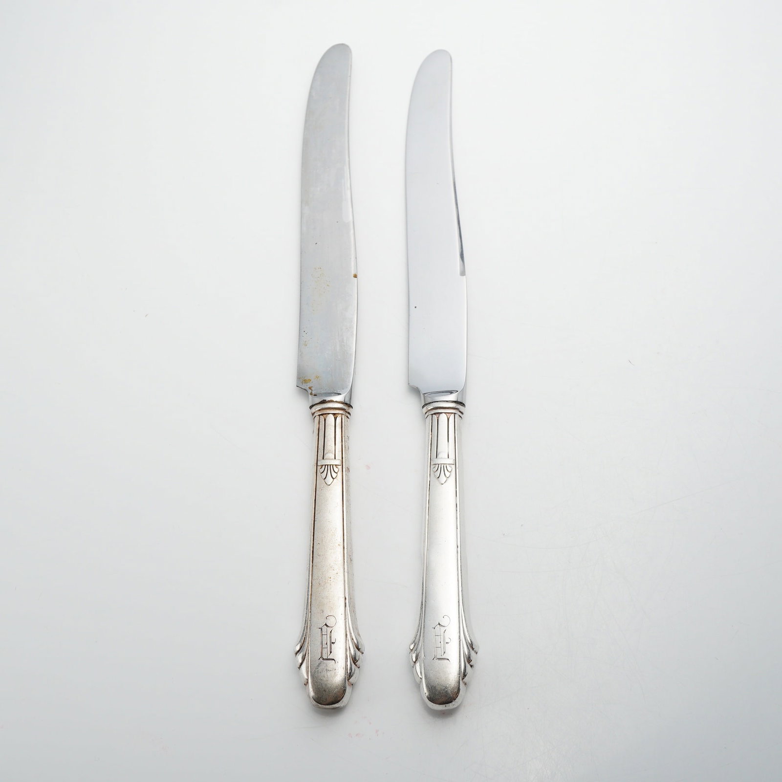 Pair of Gorham Sterling Silver Handled Table Knives: This lot produced by the Gorham Manufacturing Company of Providence, Rhode Island. The knives exhibit a neoclassical design with fluted handles and a stylized foliate or shell motif at the bolster.