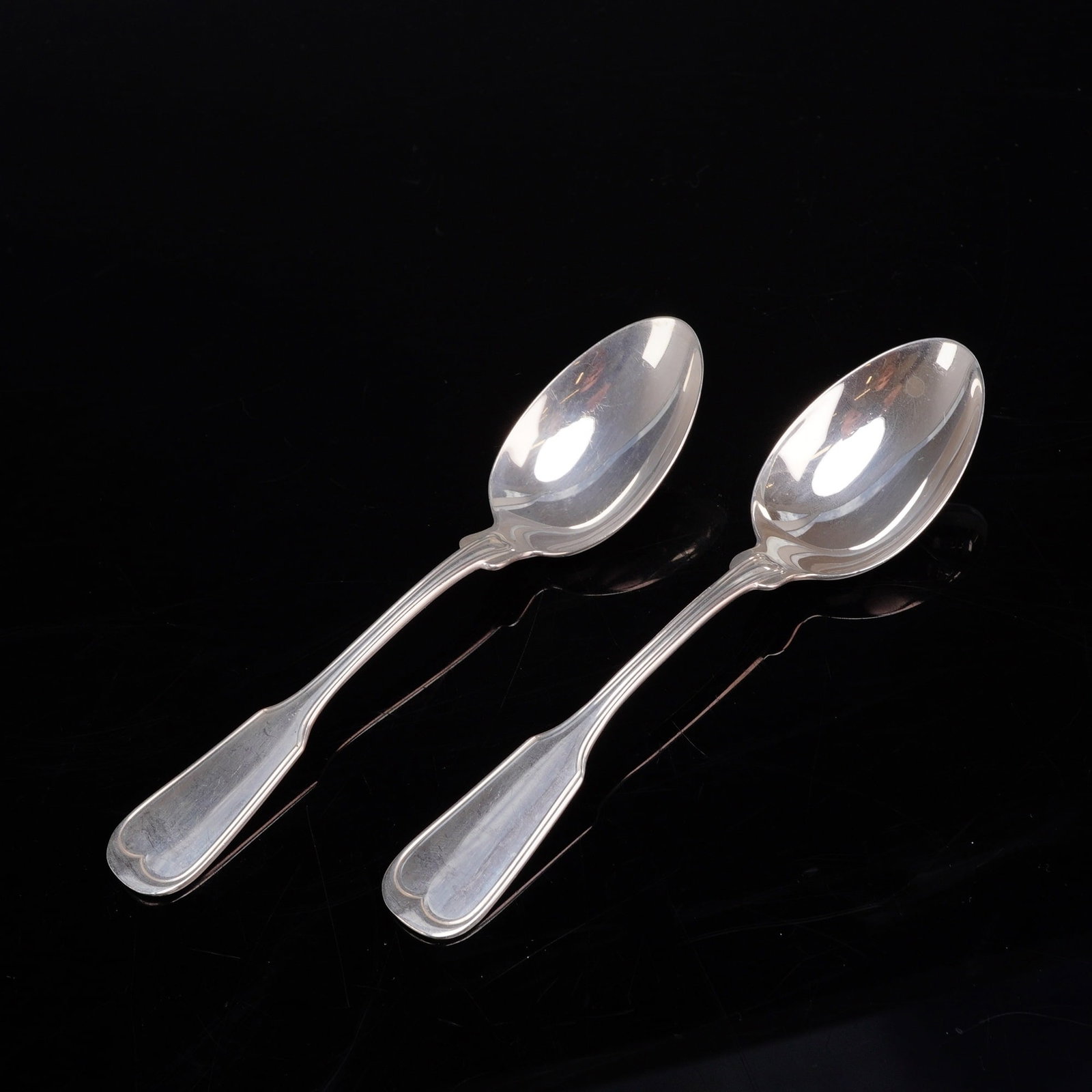 A Pair of Frank W. Smith Silver Co. Sterling Silver Teaspoons in the Fiddle Thread Pattern: A pair of sterling silver spoons by Frank W. Smith Silver Co. Each spoon features a fiddle-shaped handle with a raised thread-line border and a scalloped, trilobed terminal. The spoons have oval bowls