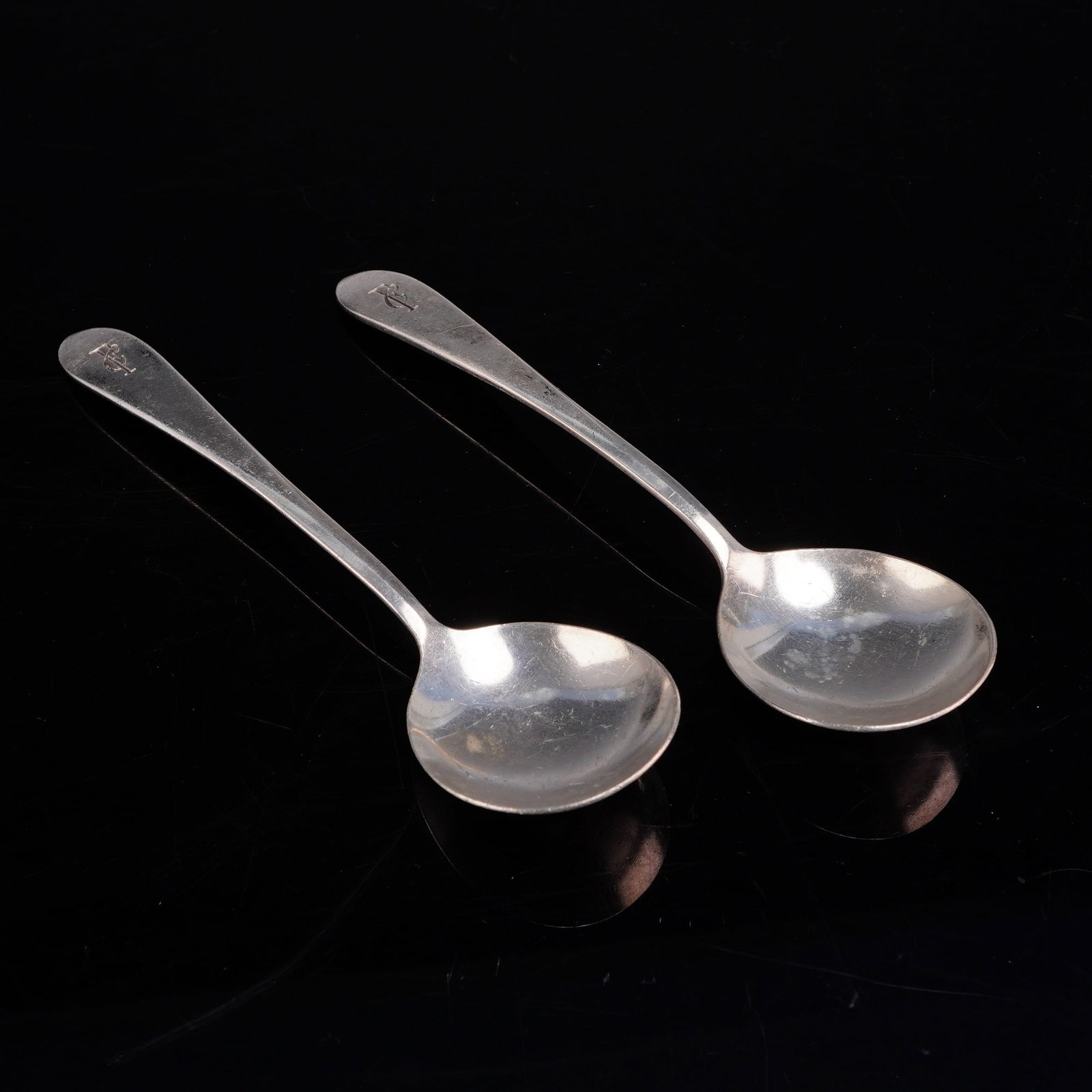 A Pair of International Silver Co. Silver-Plated Spoons: A pair of silverplated spoons produced by the International Silver Co. These items are designed as bouillon or cream soup spoons, featuring rounded bowls and smooth, tapered handles. Each spoon is